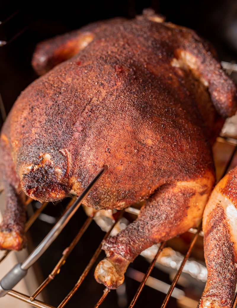 chicken in smoker getting its temperature taken