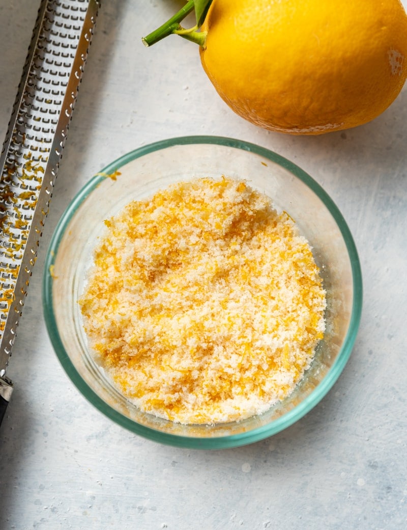 lemon zest mixed with sugar in a small glass bowl, zester took, lemon