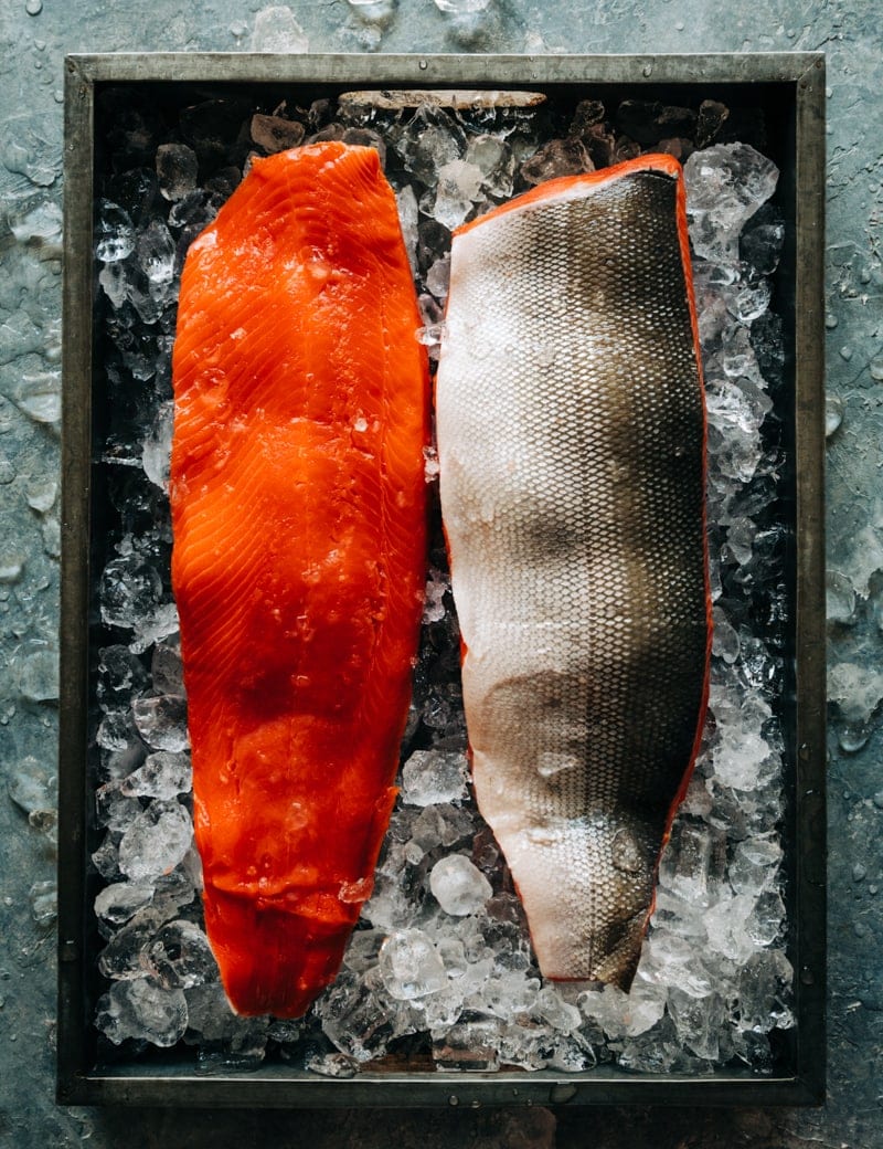 Two wild Alaskan sockeye salmon fillets on ice in a tray