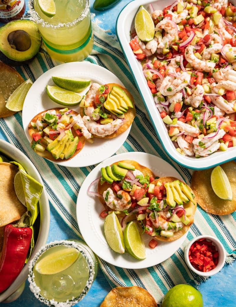 two small plates of mini shrimp ceviche tostadas, tray of shrimp ceviche, lime slices, avocado, margaritas 