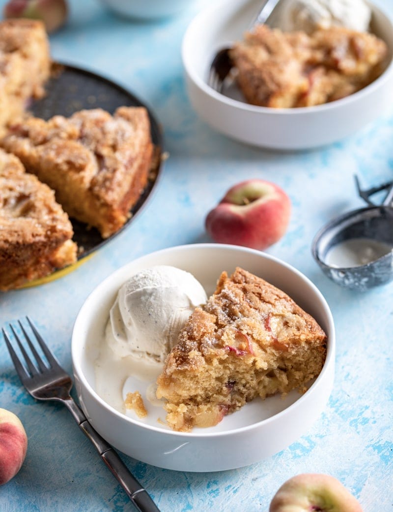 angled photo of Summertime Brown Sugar White Peach Buttermilk Cake slice with ice cream. www.pineappleandcoconut.com