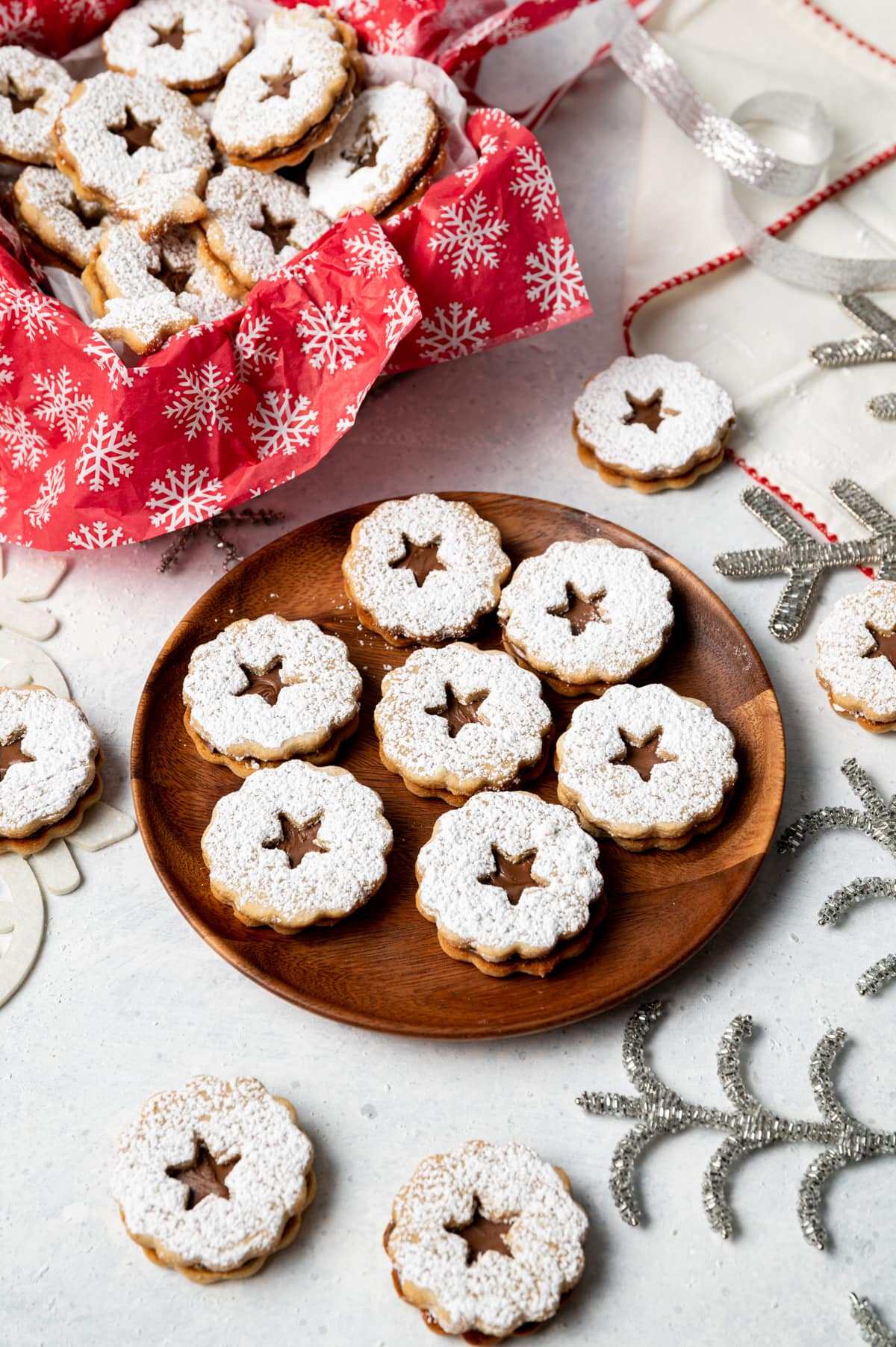 chocolate filled sandwich cookies on a wood plate and chocolate filled sandwich cookies in a box with red and white snowflake paper