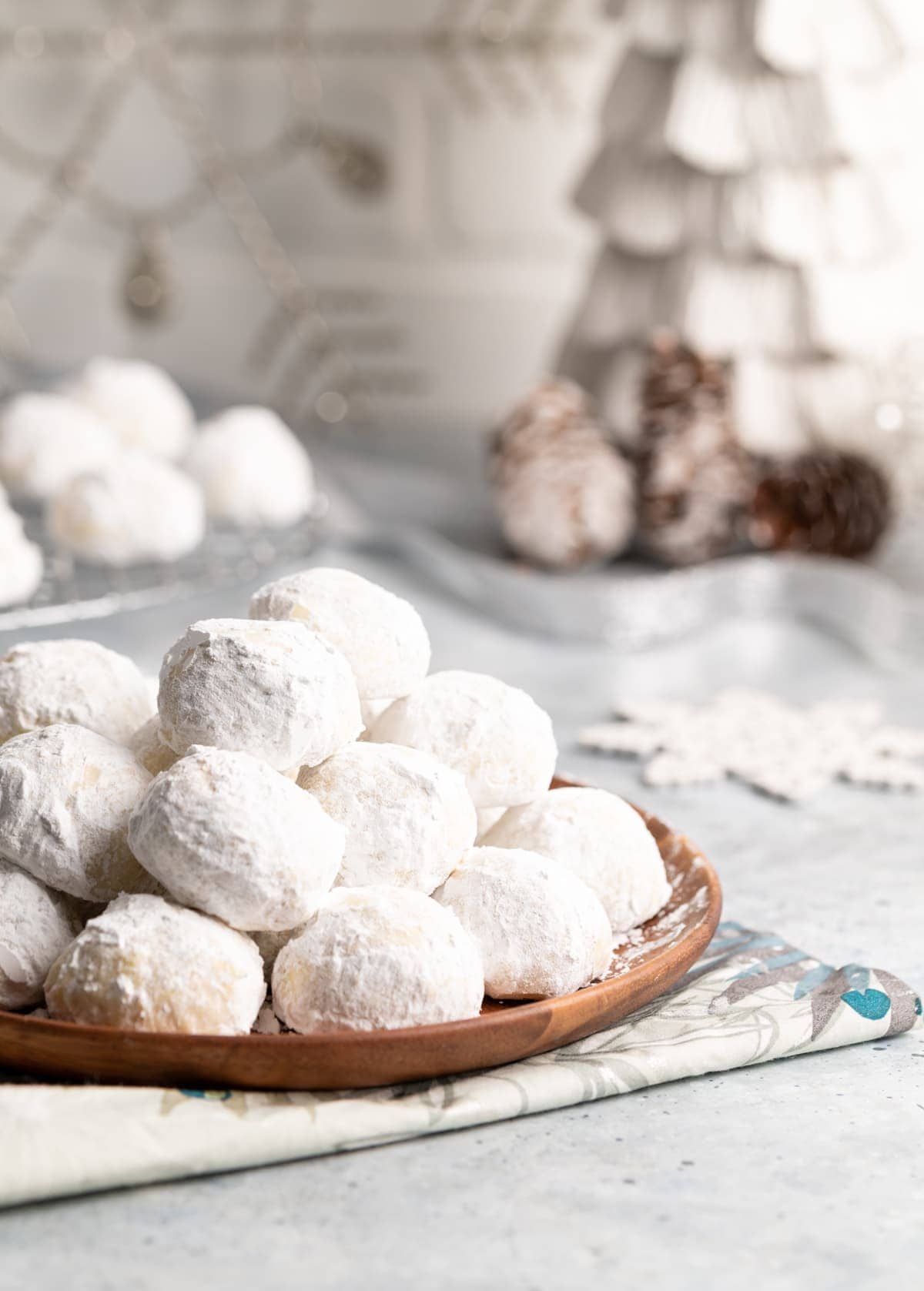 small round cookies covered in powdered sugar on a brown plate