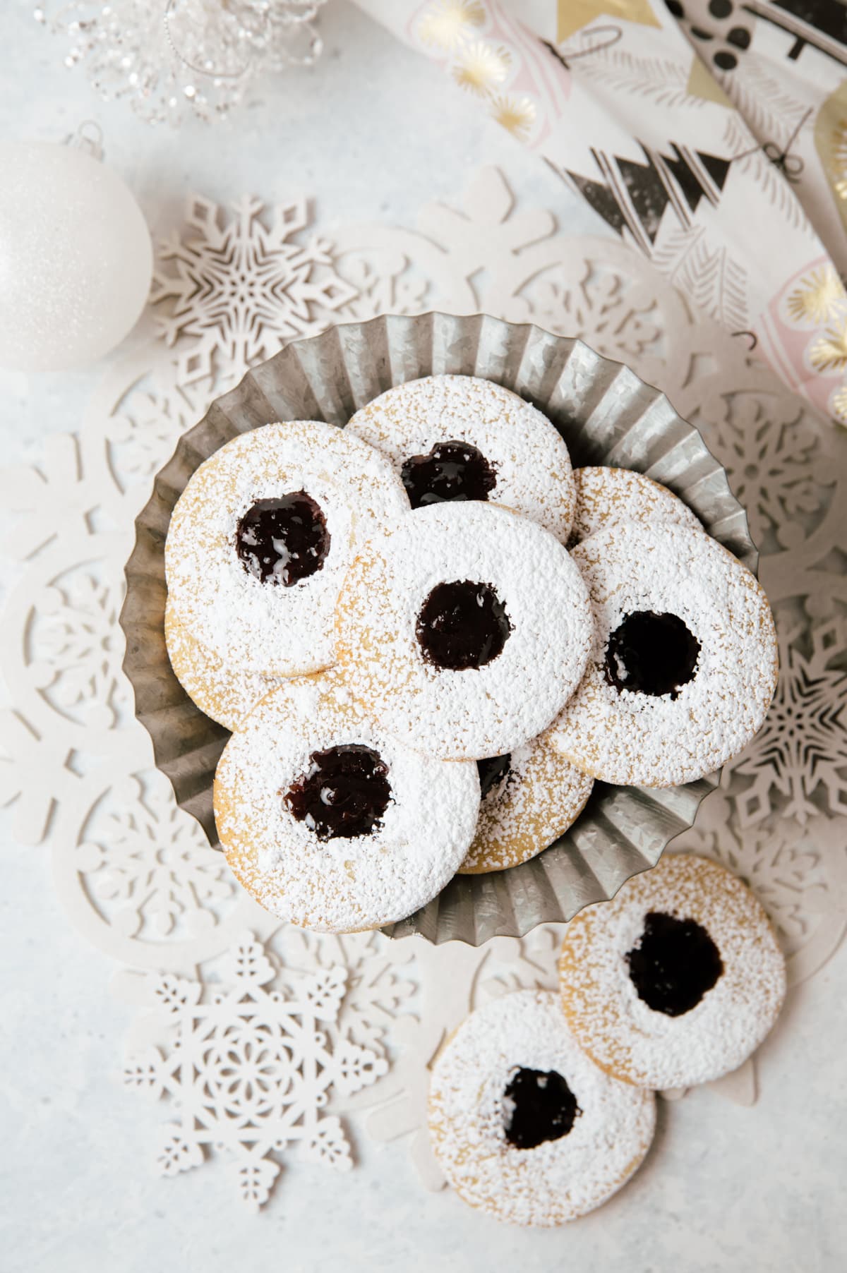 round sandwich cookies with dark purple jam layered on a metal cake plate
