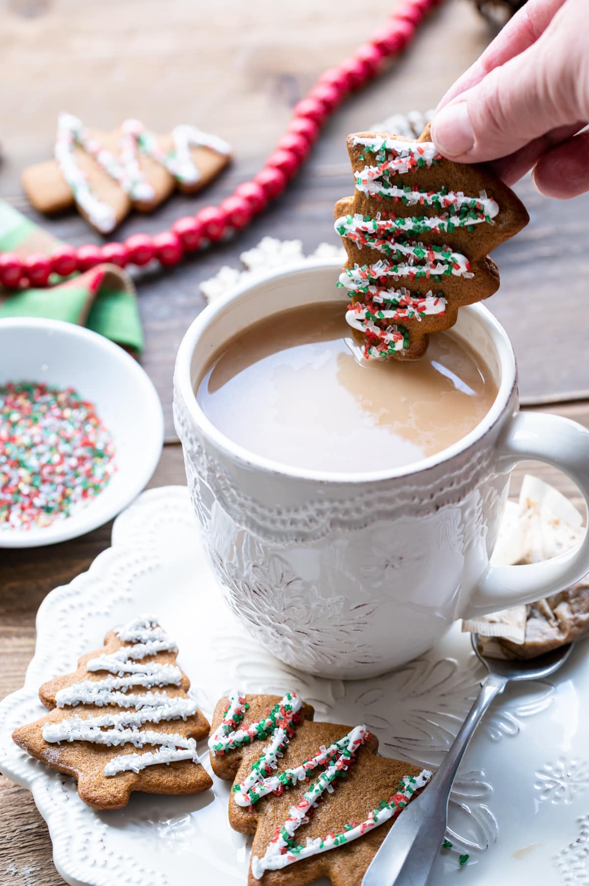 gingerbread christmas tree cut out cookie being dipped into a cup of tea