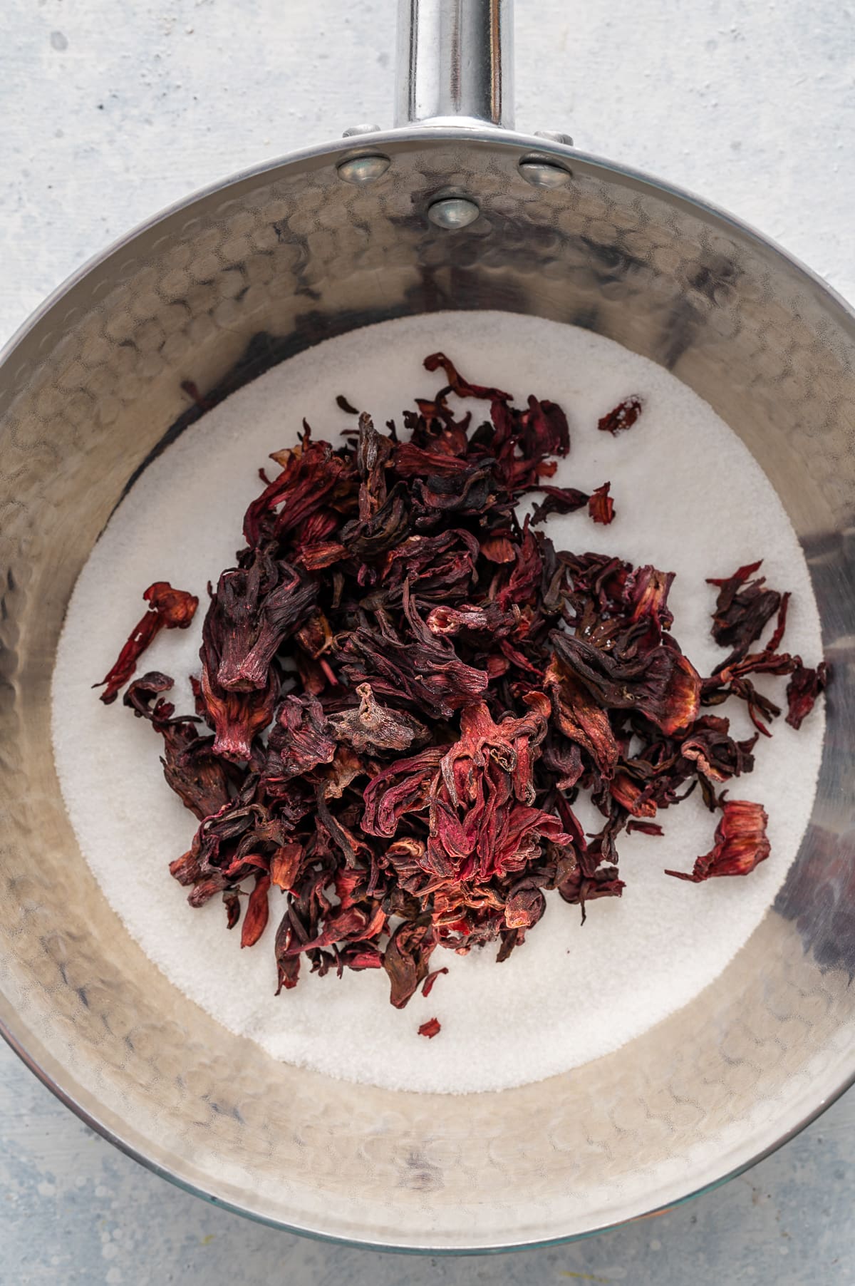 saucepan filled with sugar and dried red hibiscus flowers