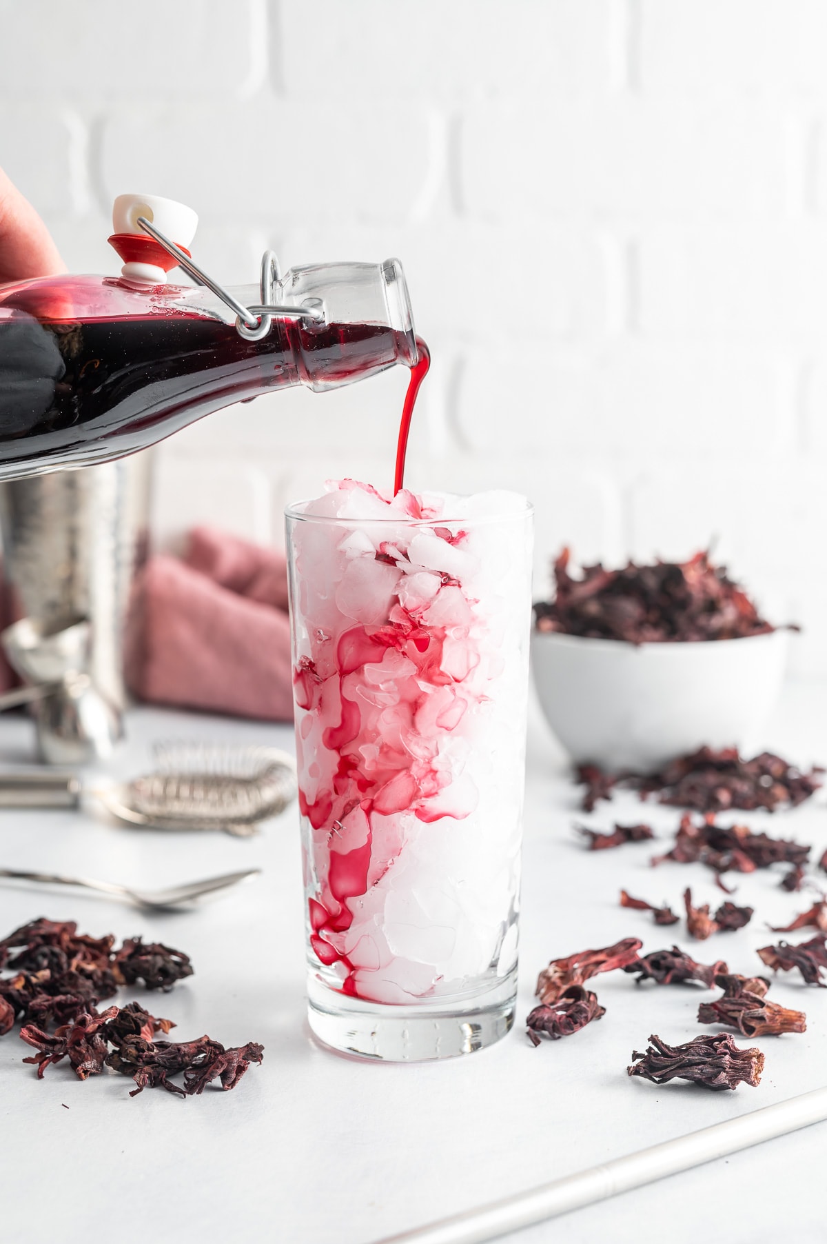 dark red hibiscus syrup being poured into a glass filled with ice