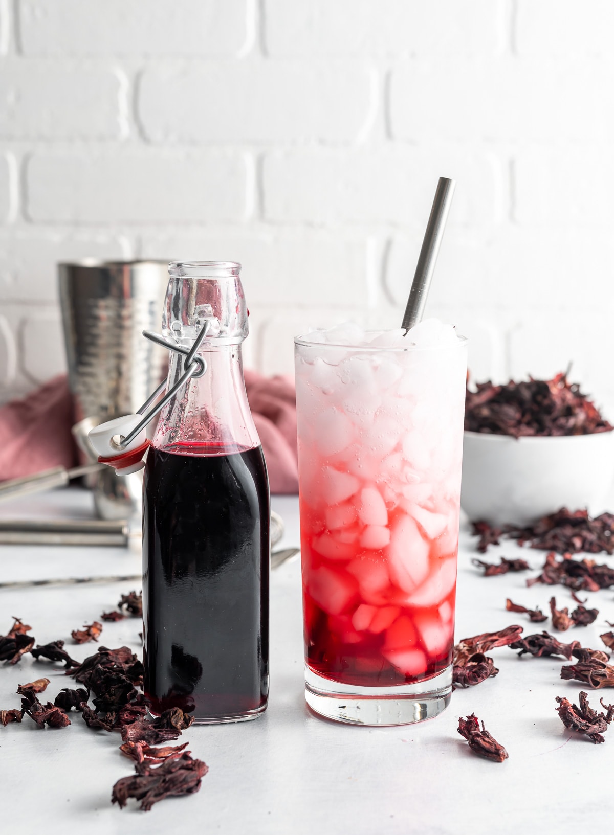 bottle of dark red hibiscus syrup in a bottle glass with ice with syrup and soda