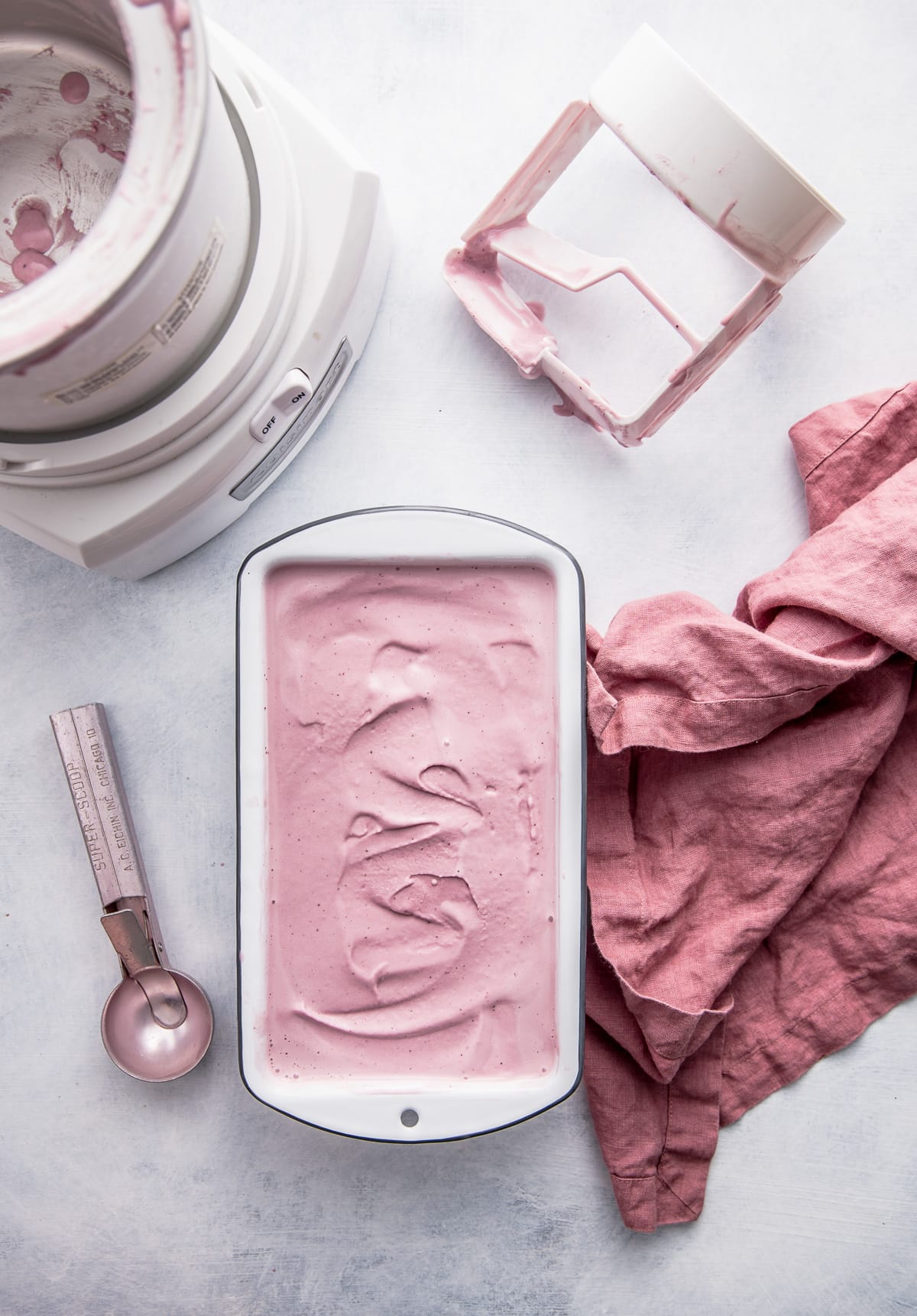 pink ice cream in a loaf pan with ice cream maker pink napkin and pink ice cream scoop