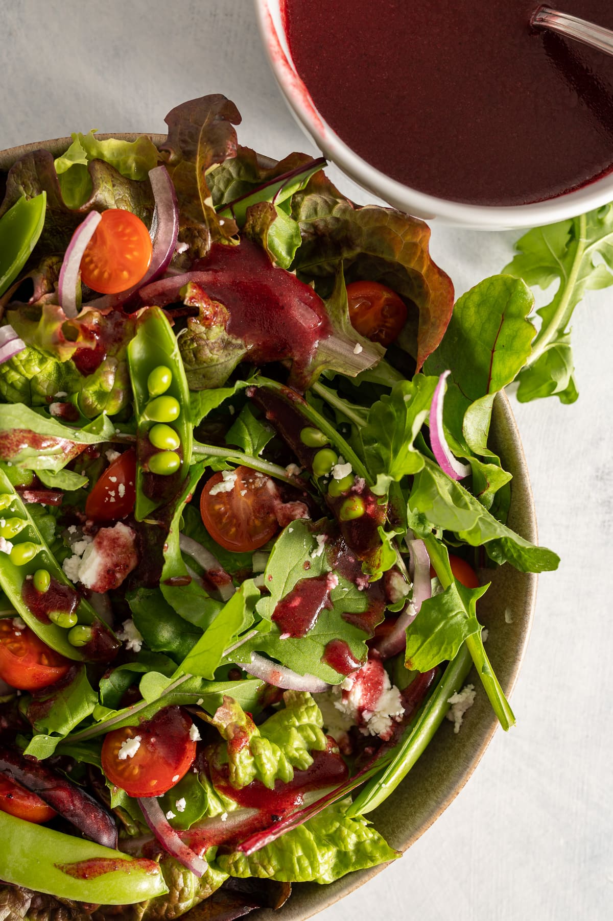 close up of a bowl of salad greens with dark red hibiscus vinaigrette dressing 