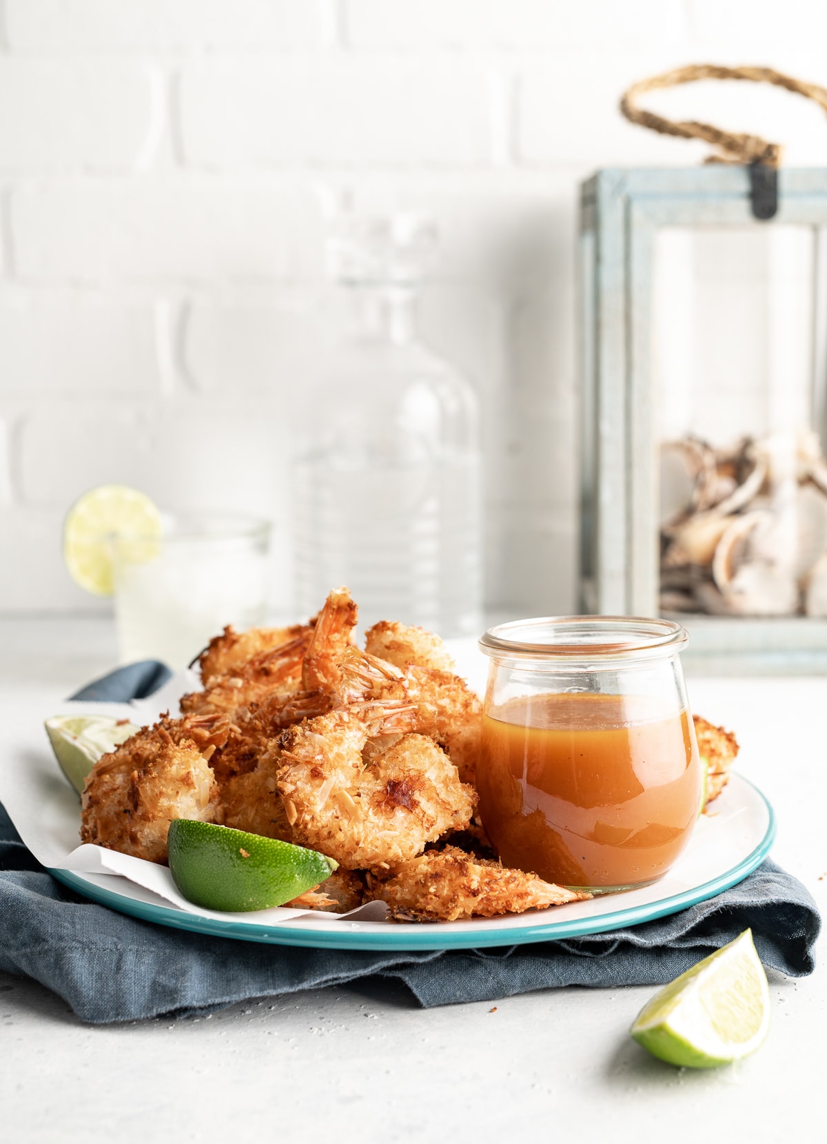 plate of coconut shrimp with a jar of habanero passion fruit dipping sauce with lime slices