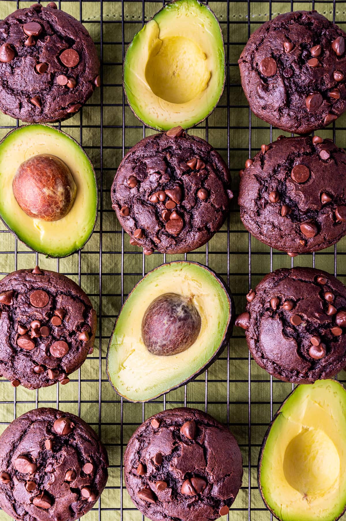chocolate avocado muffins on wire cooling rack with avocados cut in half