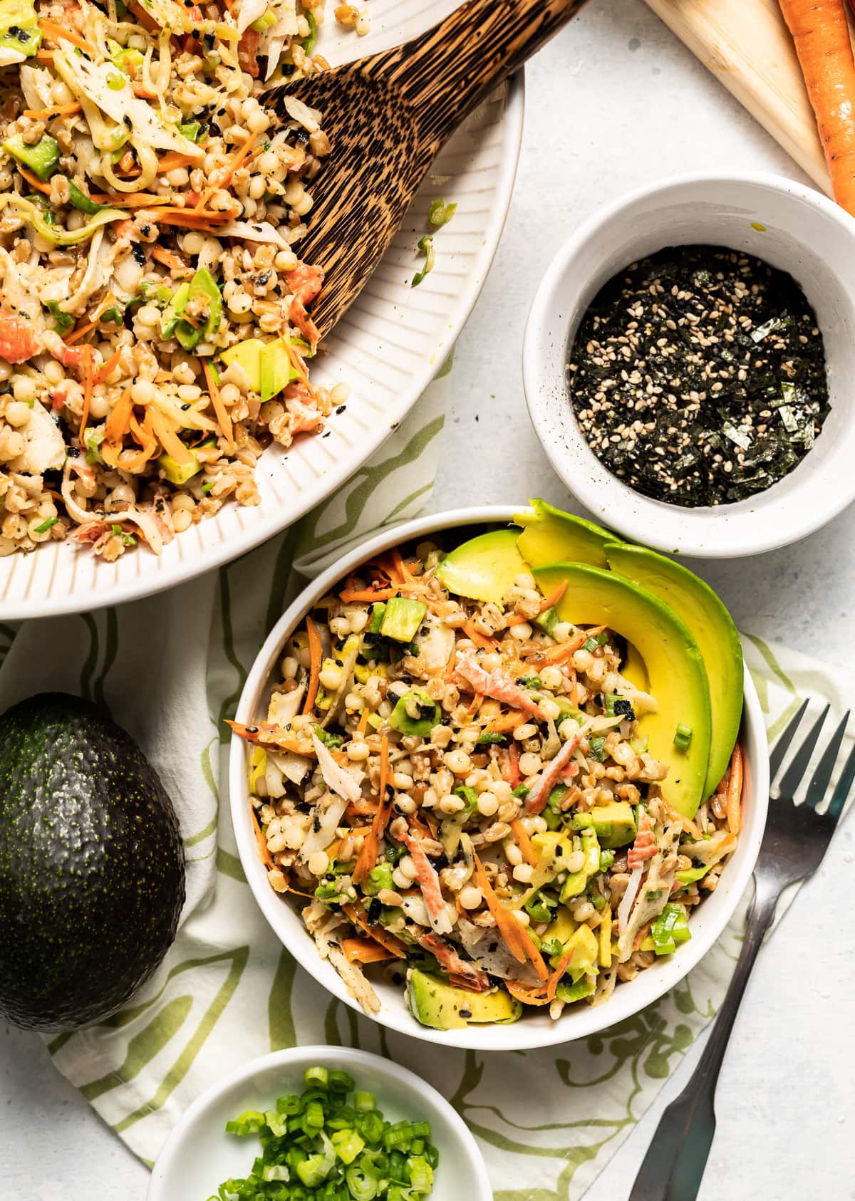 california roll salad with mixed grains and vegetables in white bowls bowl or green onion whole avocado bowl of seaweed seasoning