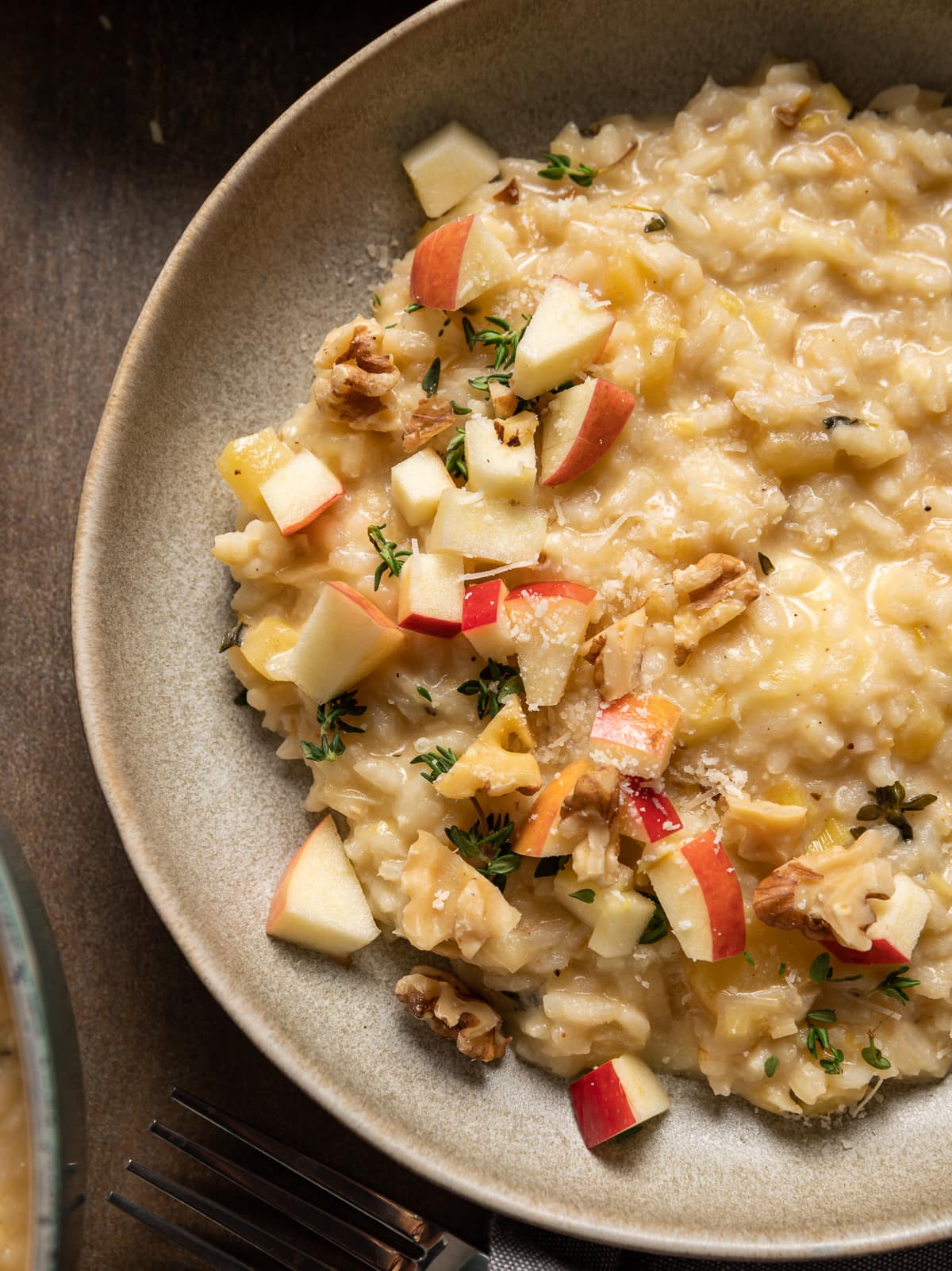 beige bowl with brie risotto topped with apple pieces walnuts and thyme