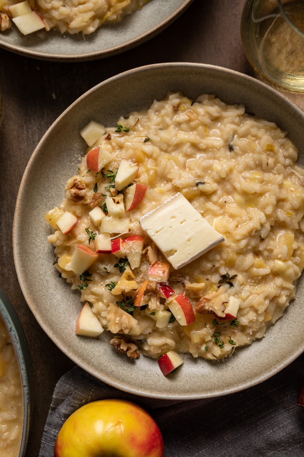 beige bowl with yellow brie risotto with apple pieces walnut pieces a wedge of brie cheese