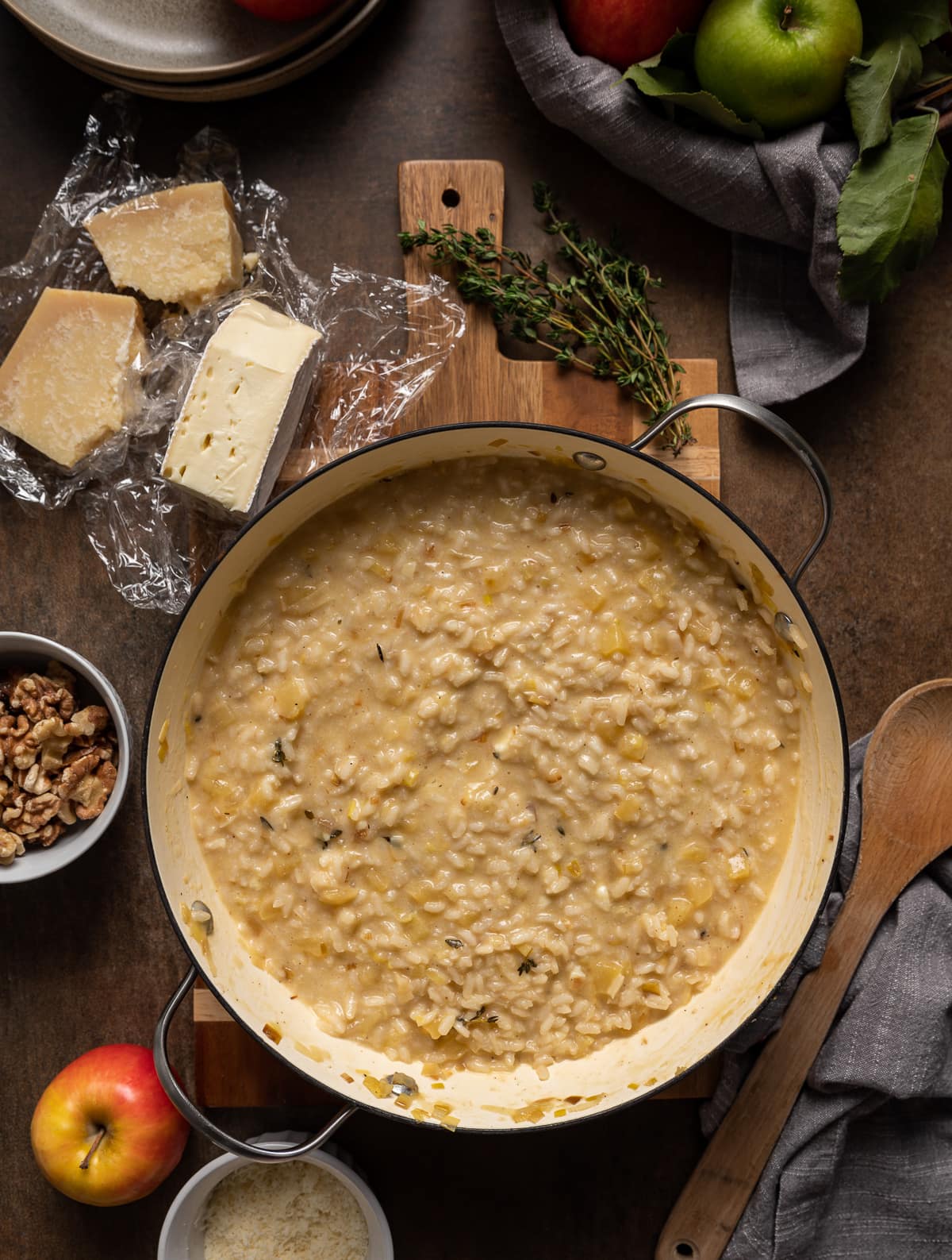creamy brie risotto in enamel pan with pieces of cheese apple and walnuts