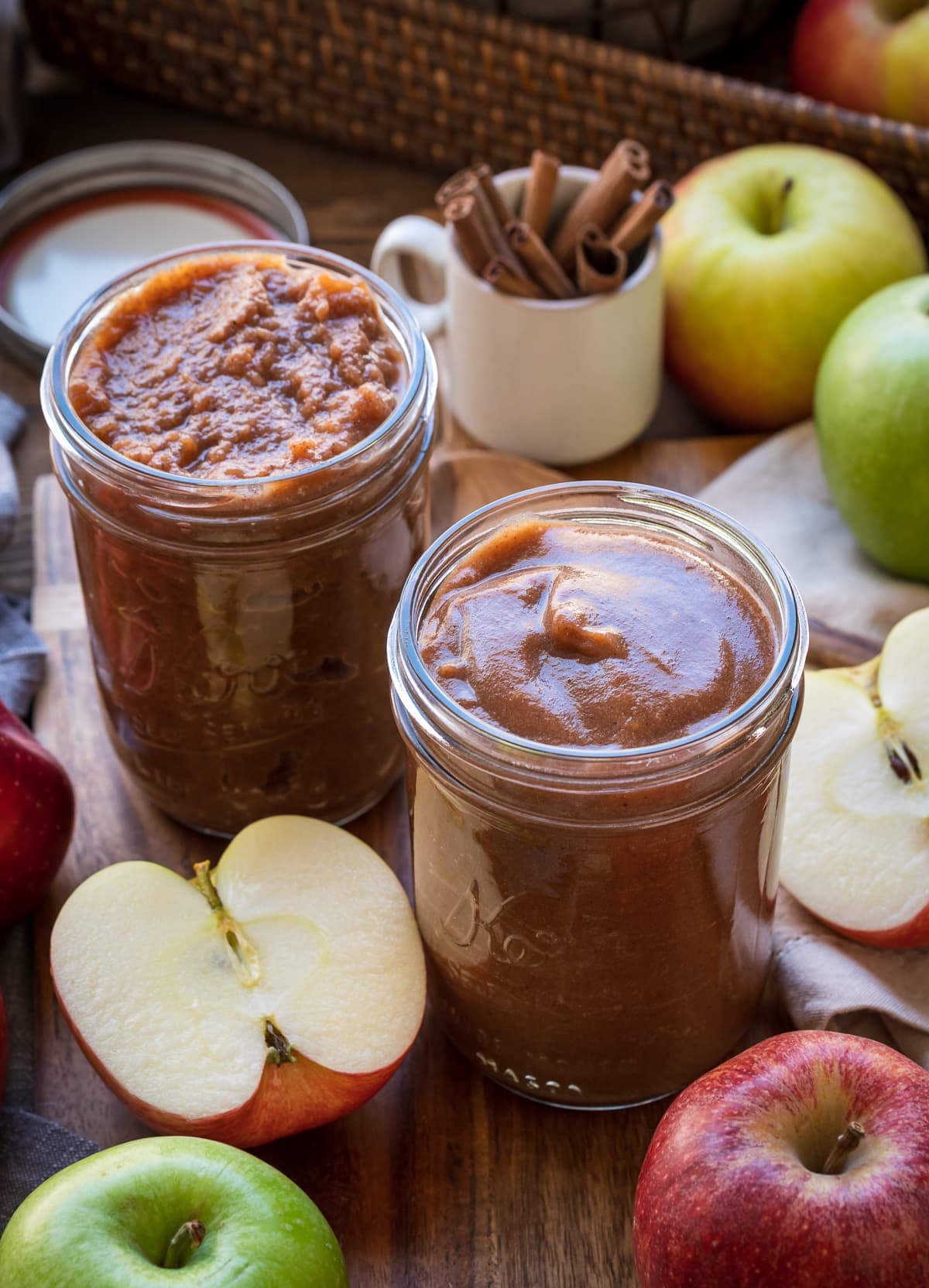 clear mason jars filled with caramel brown apple butter whole and half apples jar of cinnamon sticks