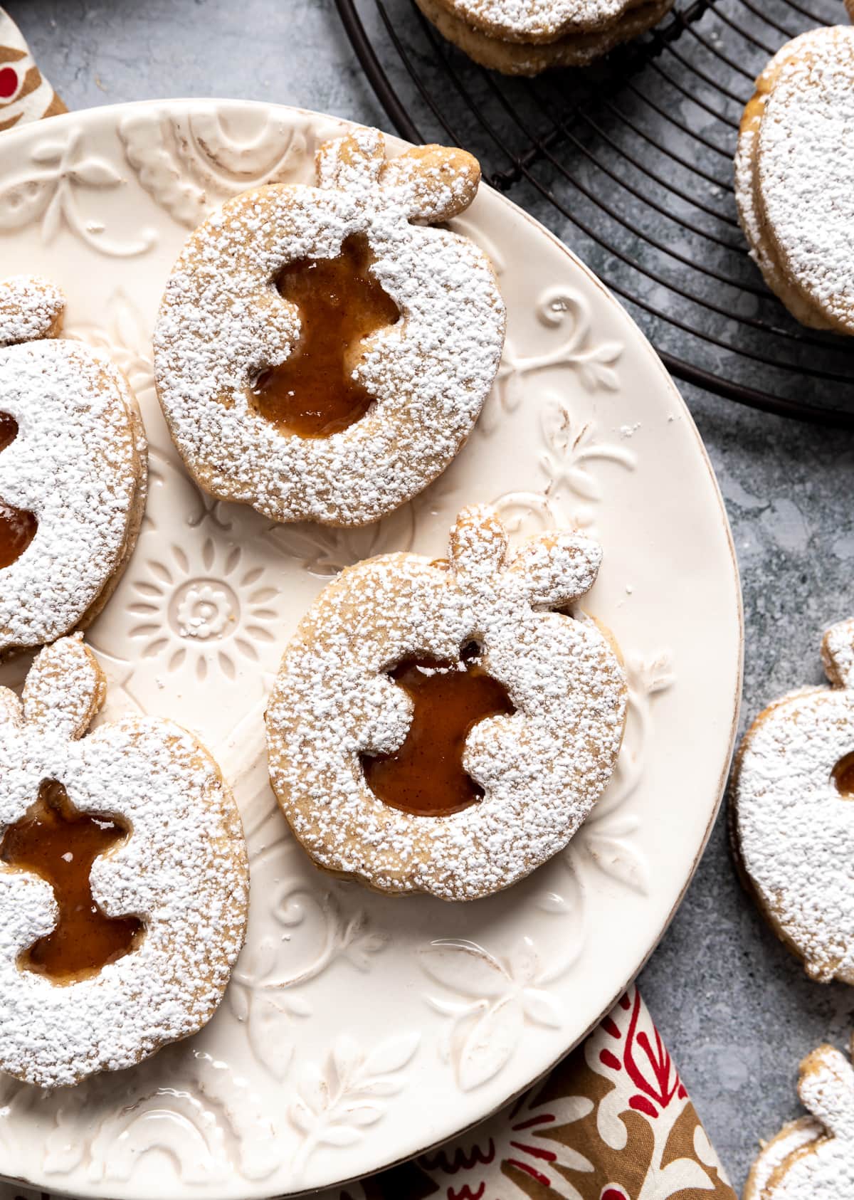 apple shaped linzer cookies with brown apple jam filling on white plate