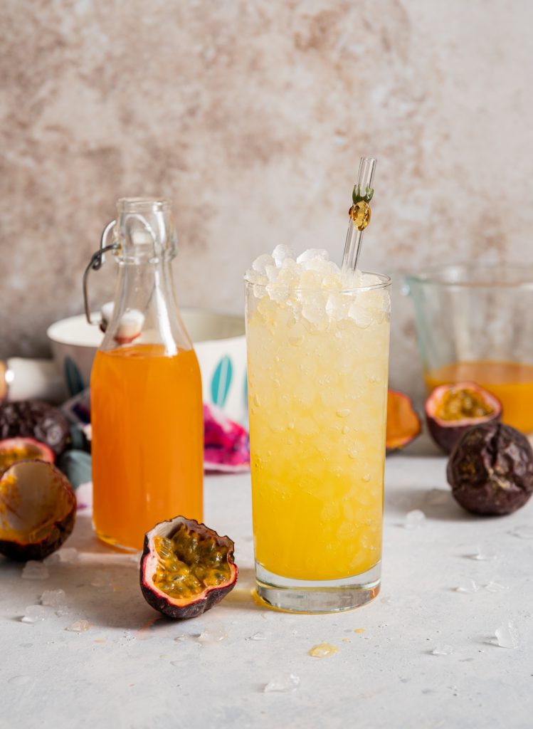 glass of passion fruit soda with passion fruits cut in half 
