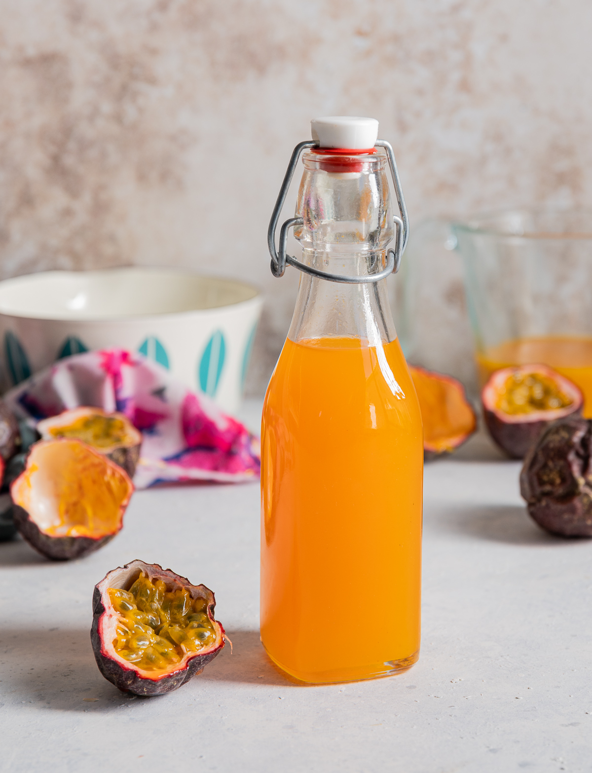 bottle with yellow orange passion fruit simple syrup fresh passion fruit cut in half