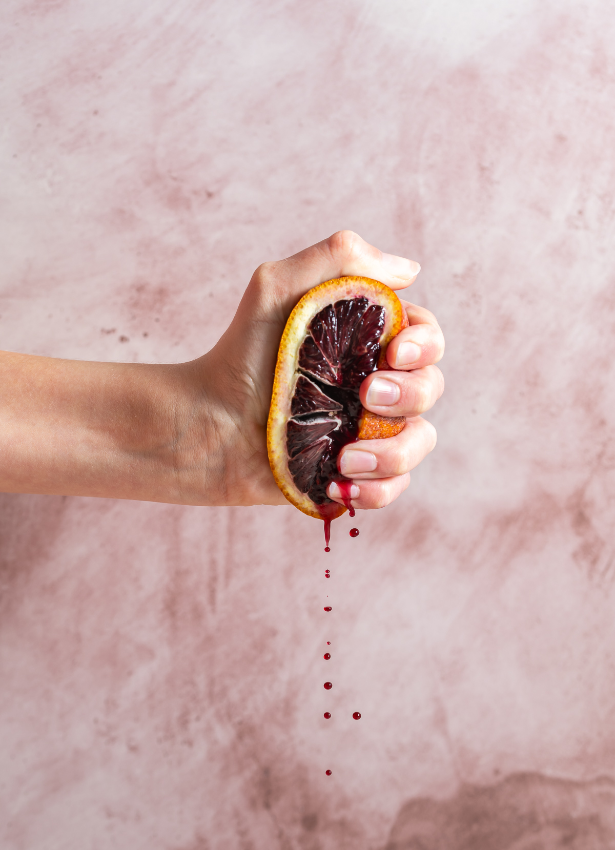 hand squeezing half of a blood orange