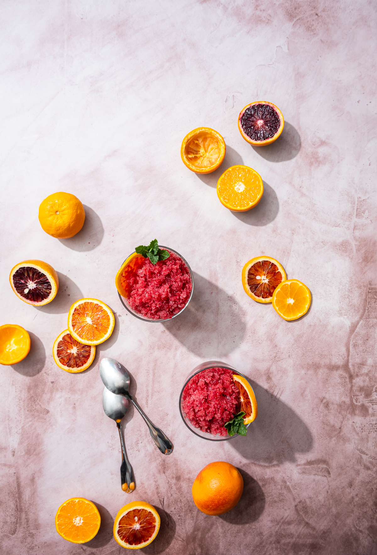 reddish orange blood orange granita in glasses spoons blood orange and tangerine slices