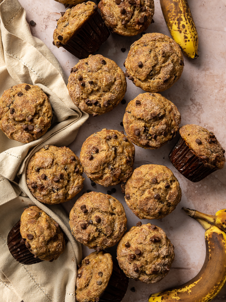 muffins in brown paper liners with chocolate chips tan napkin spotted bananas