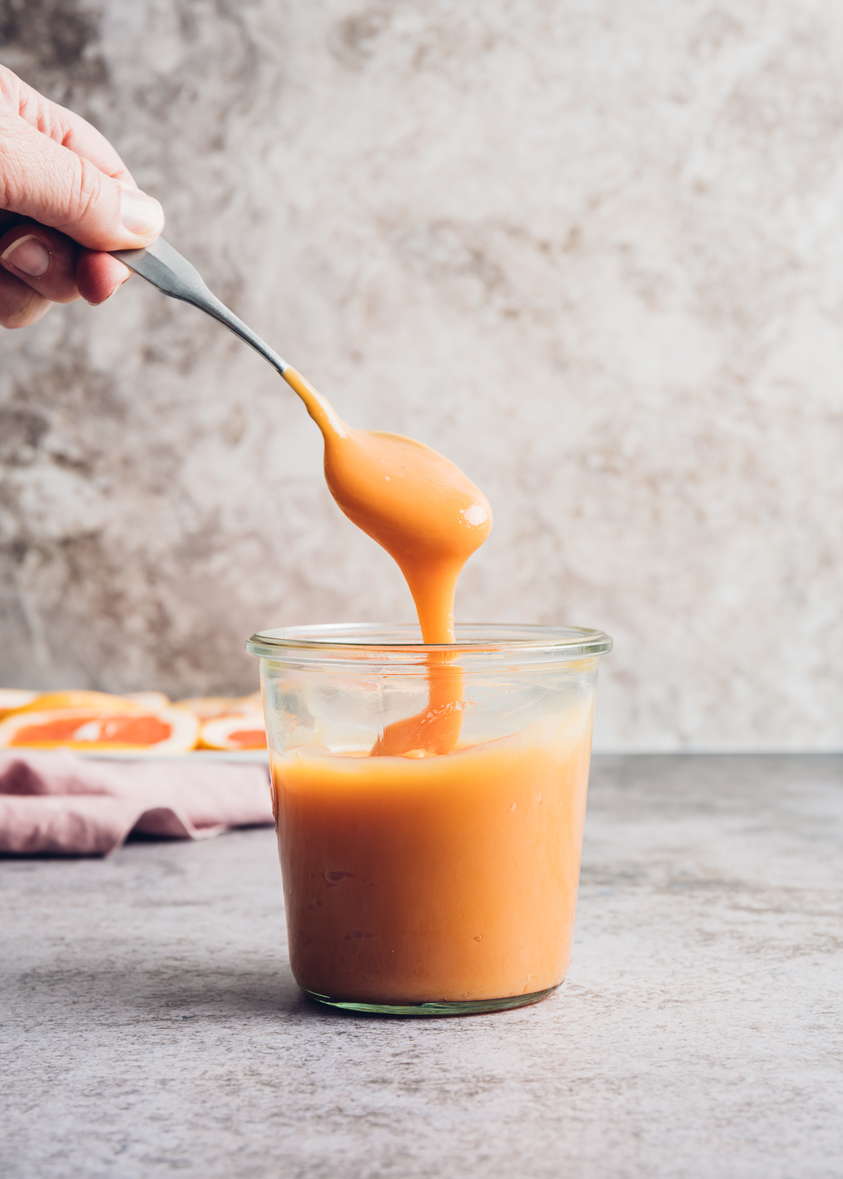 pinkish orange curd pouring off a spoon in glass jar 