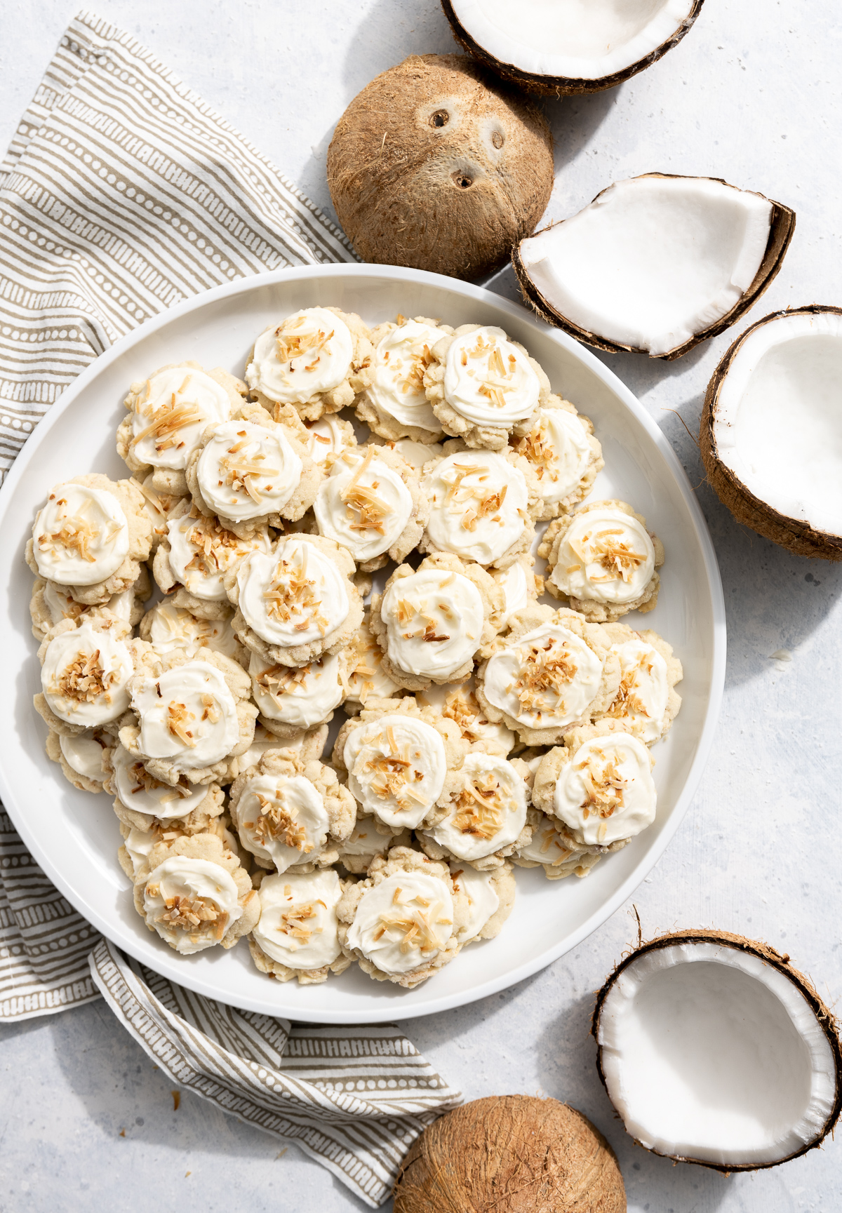 coconut cookies with coconut frosting on a white plate fresh coconuts broken into pieces