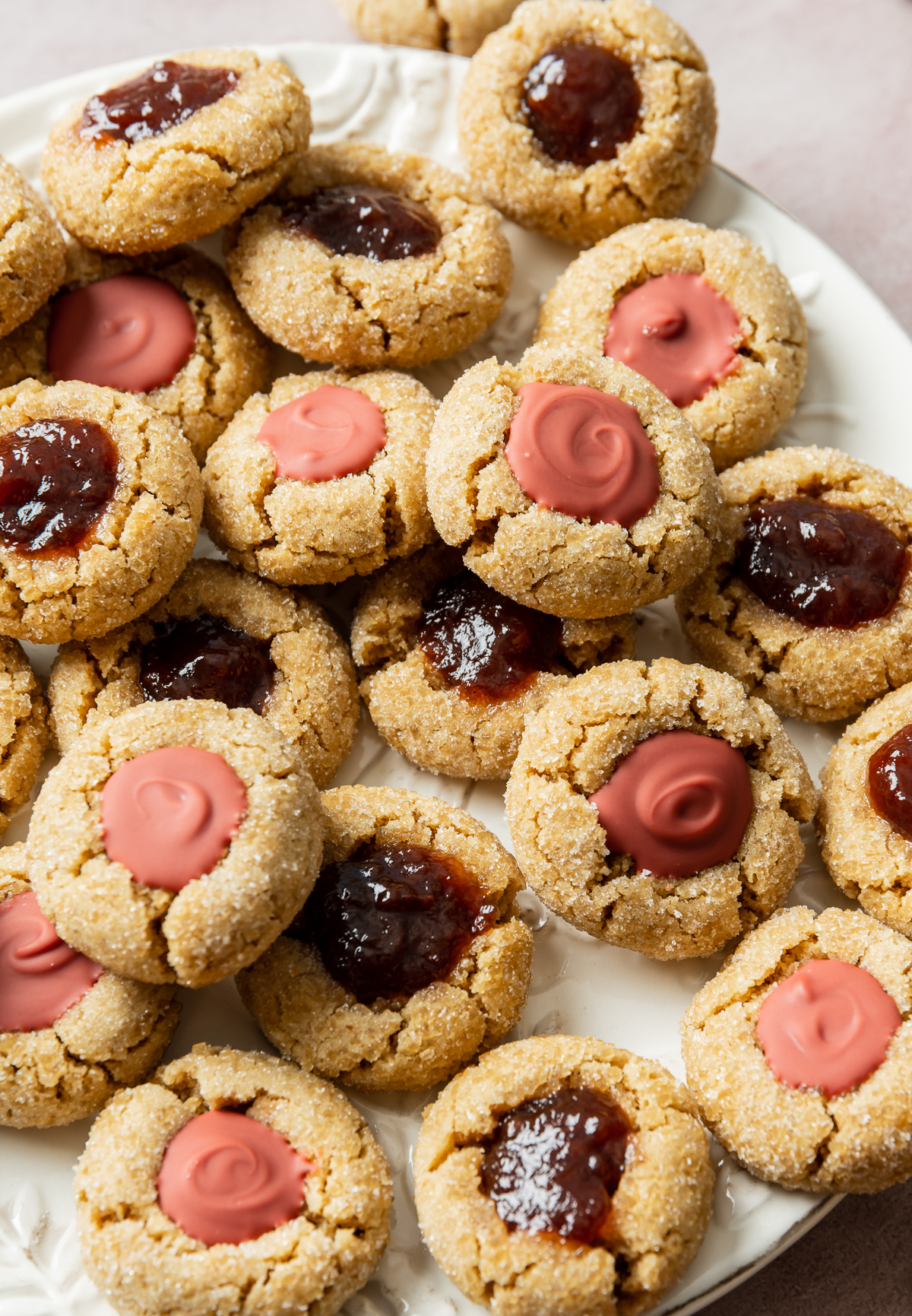 Peanut butter cookies filled with strawberry jelly and strawberry chocolate on a white plate