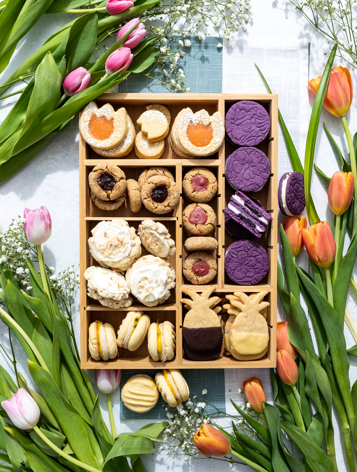 wood box of various cookies with fresh tulips around the box