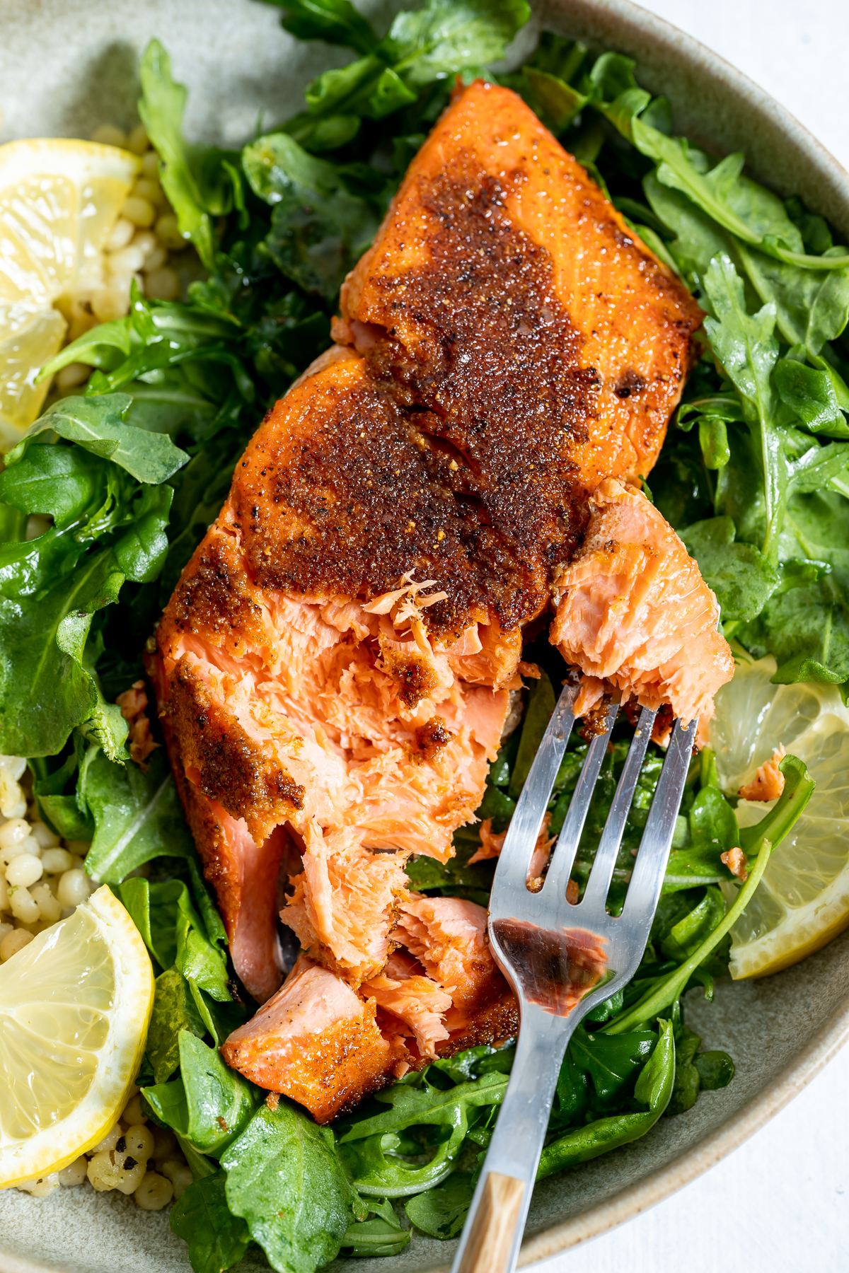 salmon fillet on plate over bed of arugula 