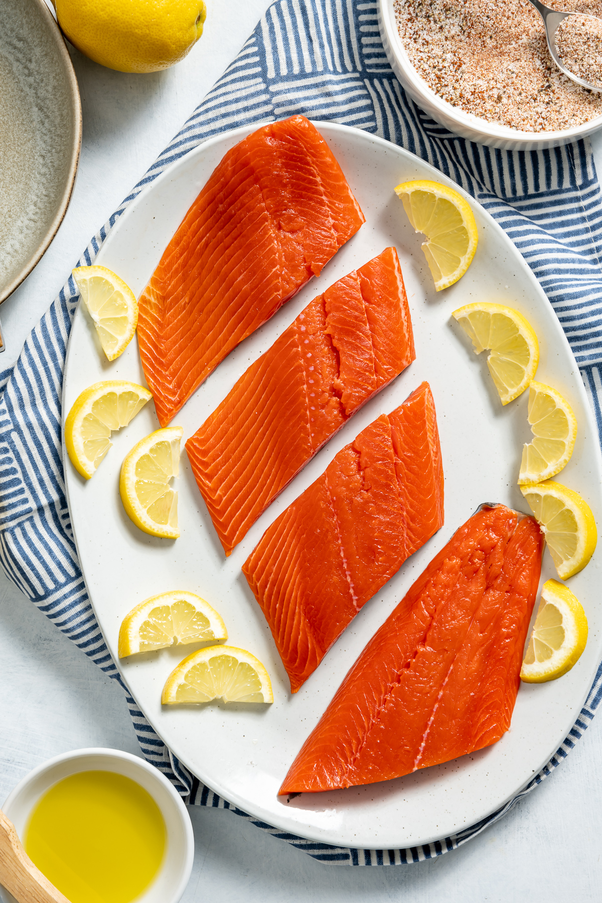 white plate of four salmon fillets lemon slices