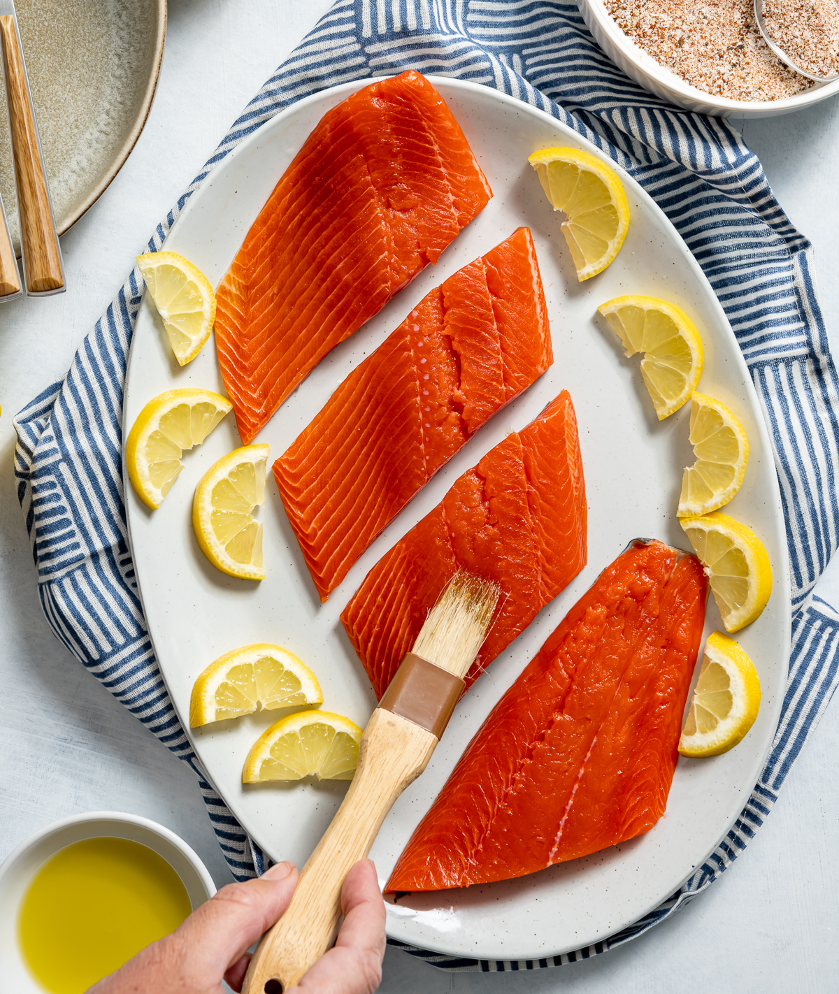 white plate of four salmon fillets lemon slices