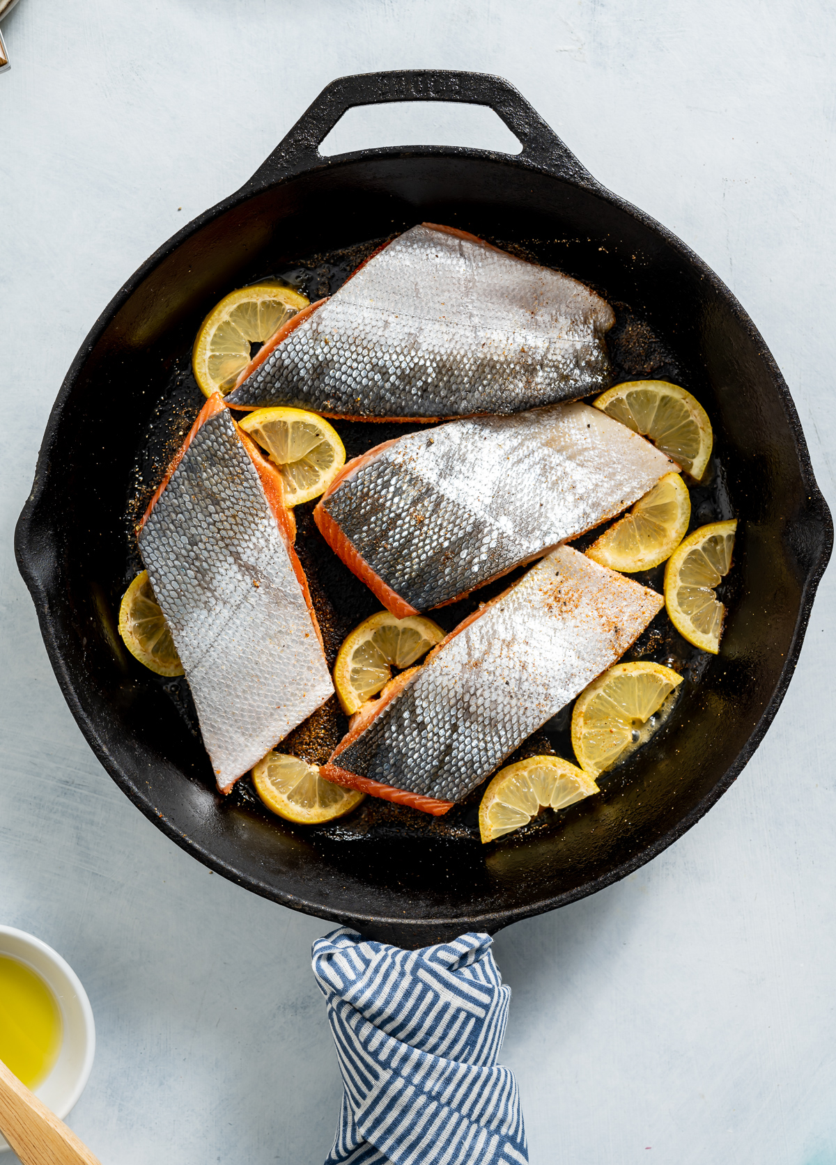 cast iron pan of salmon fillets with skin side up lemon slices
