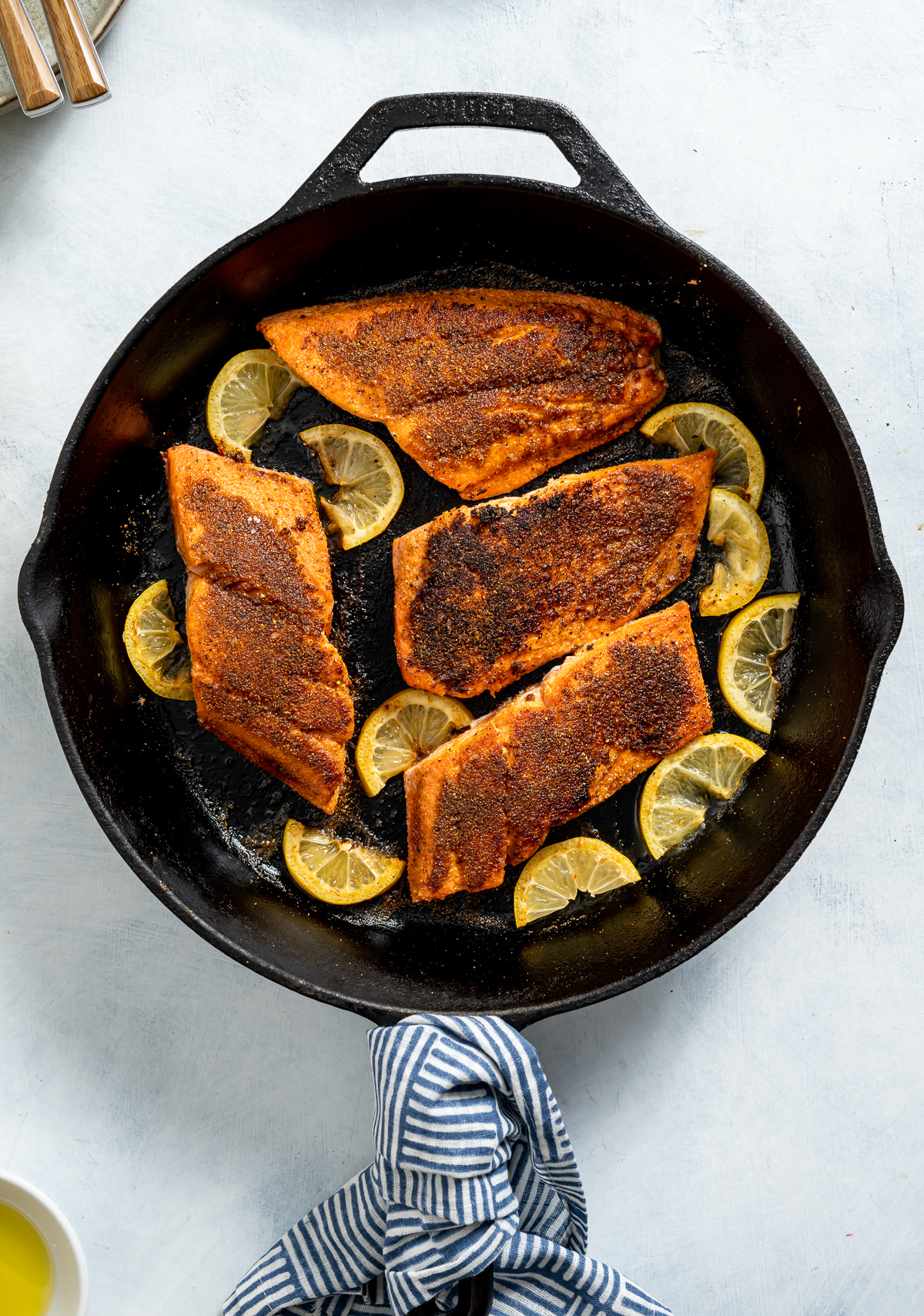 cast iron pan of cooked salmon fillets with lemon slices