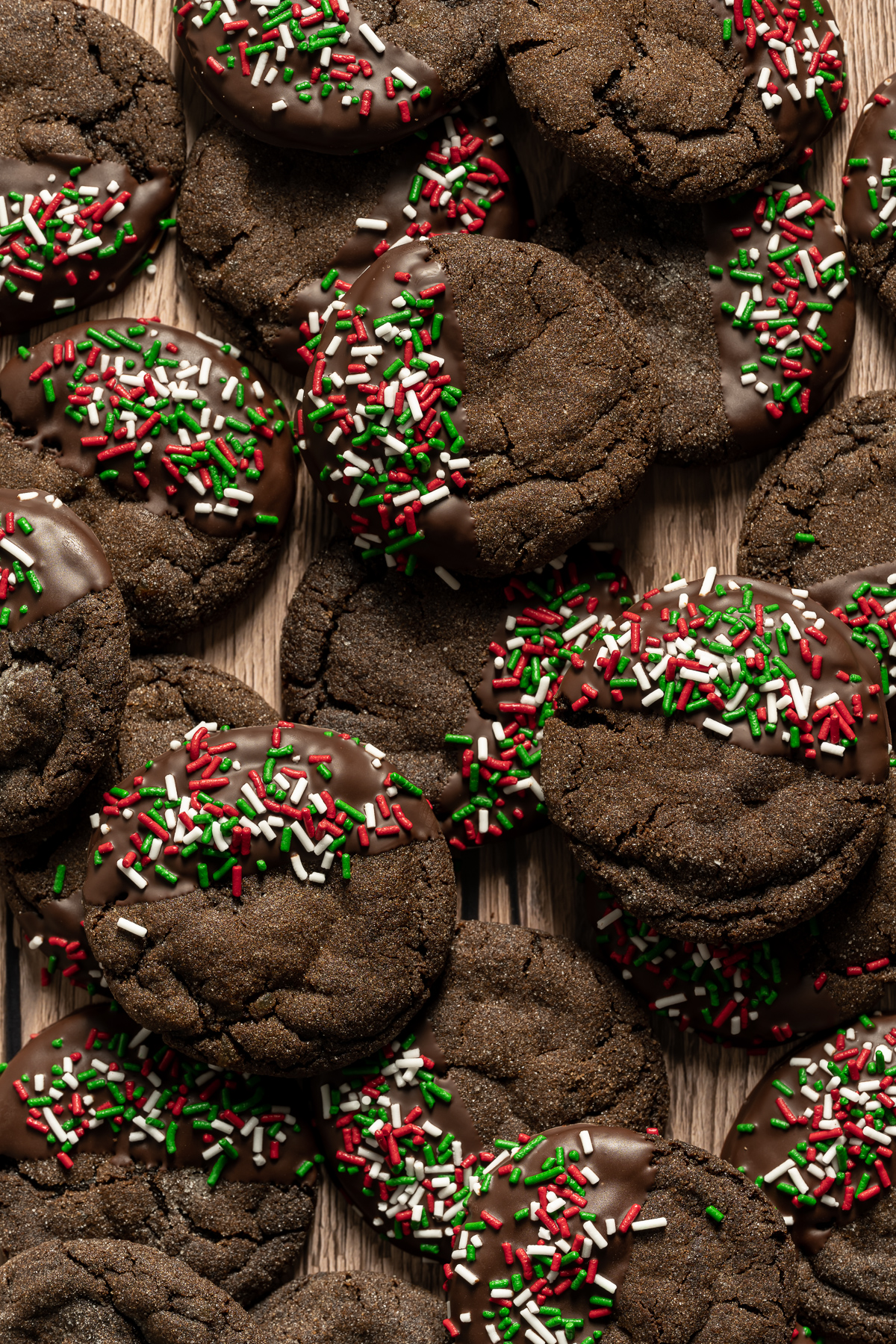 chocolate dipped chewy chocolate gingerbread cookies with red white and green sprinkles
