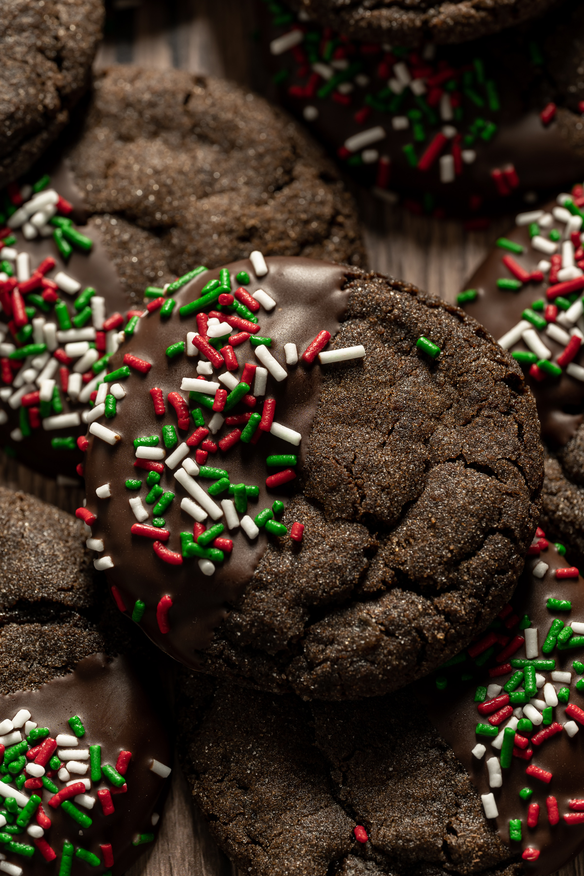 close up of chocolate dipped chewy chocolate gingerbread cookies with red white and green sprinkles
