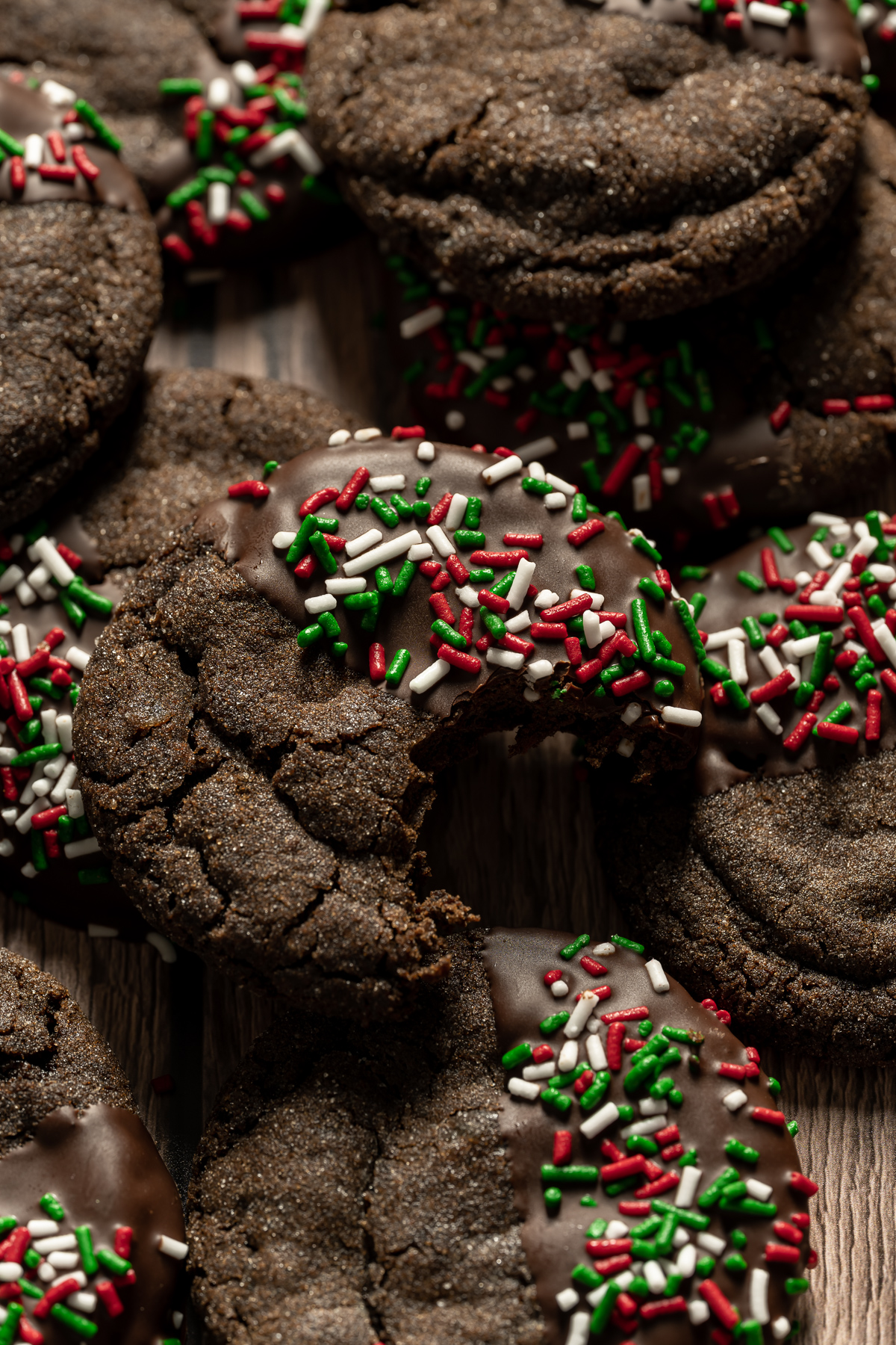 Chewy chocolate gingerbread cookies with red green and white sprinkles and a bite taken out of one cookie