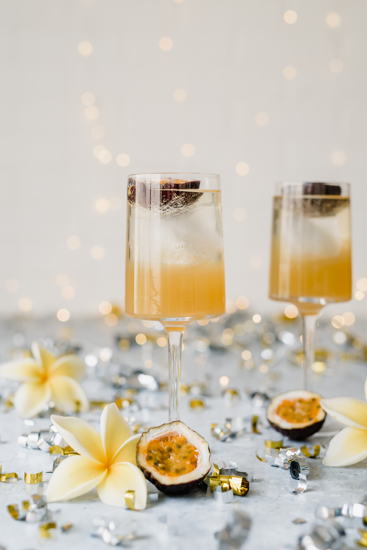 Sweet and sour passionfruit rum fizz cocktail orange liquid in two glasses with passionfruit halves