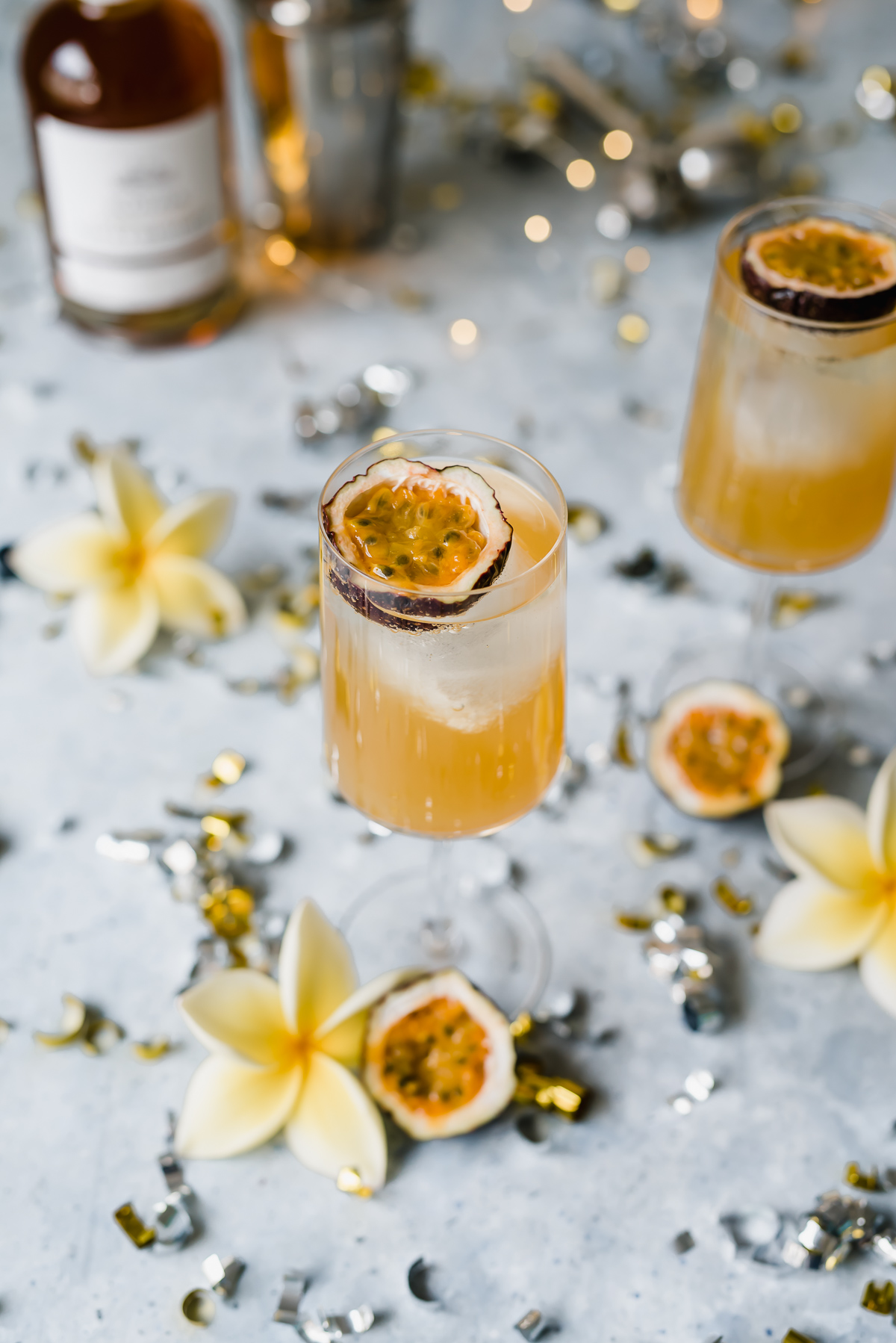 Sweet and sour passionfruit rum fizz cocktail orange liquid in two glasses with passionfruit halves