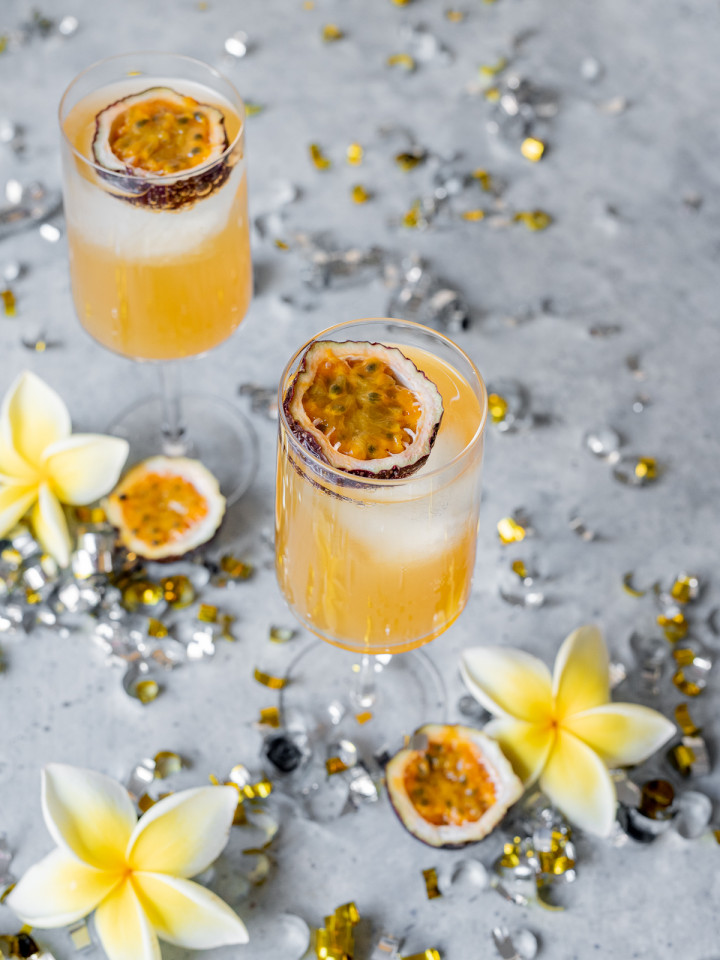passionfruit cocktail with passionfruit half silver and gold confettis yellow plumerias