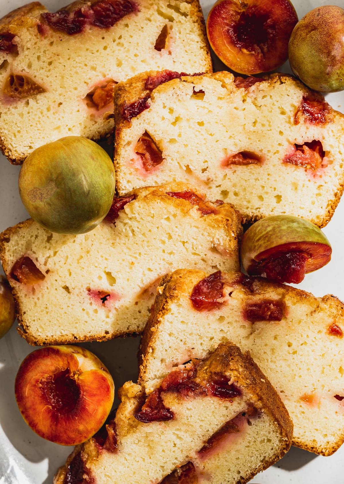 slices of plum pound cake on platter with whole and halved plums