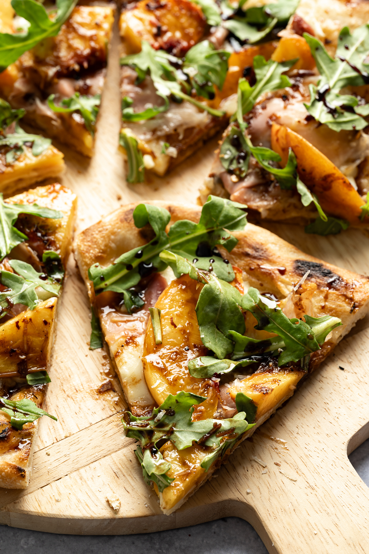 slices of grilled peach pizza with prosciutto mozzarella arugula balsamic glaze parmesan cheese