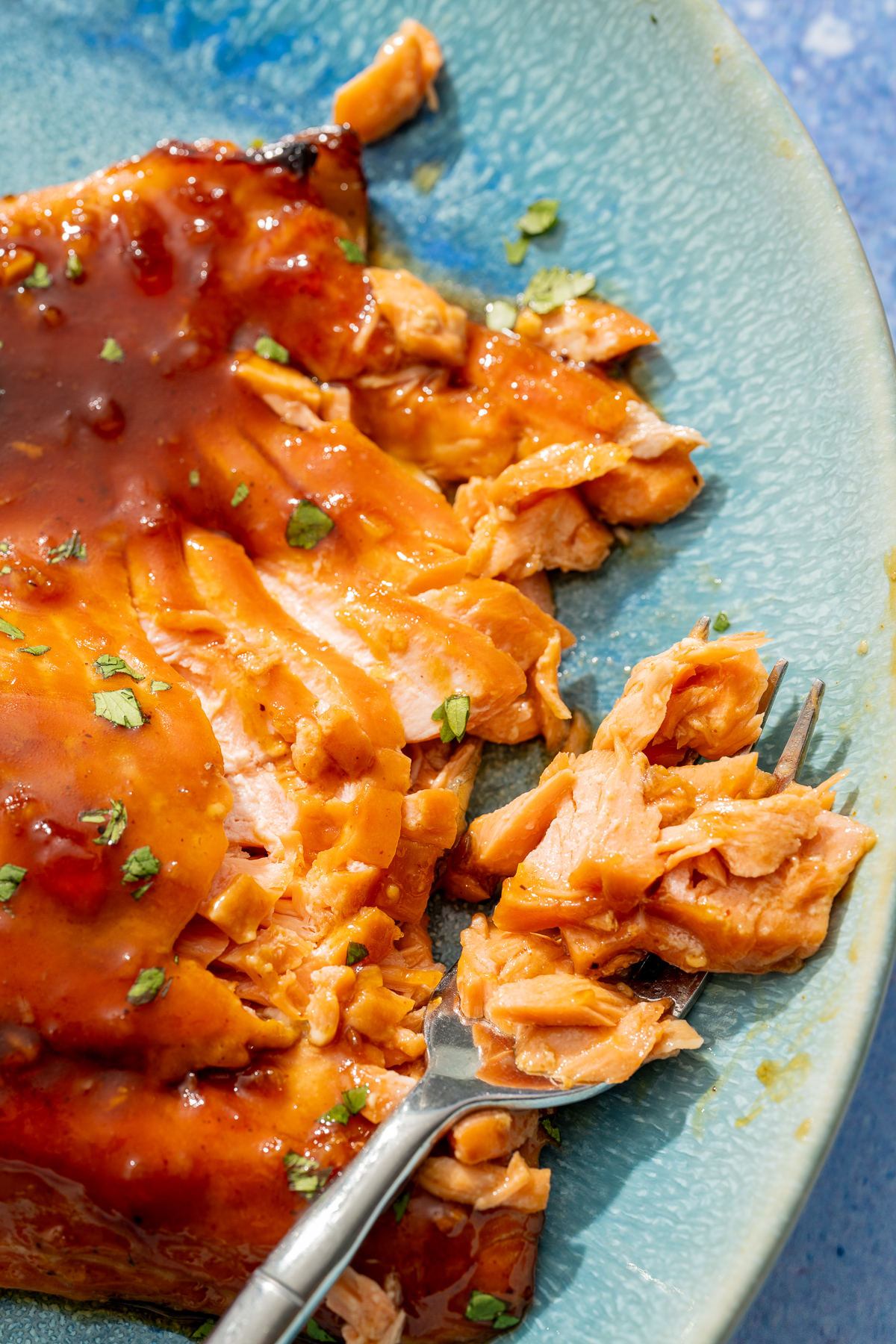 baked wild Alaskan coho salmon on a blue platter flaked apart with a fork