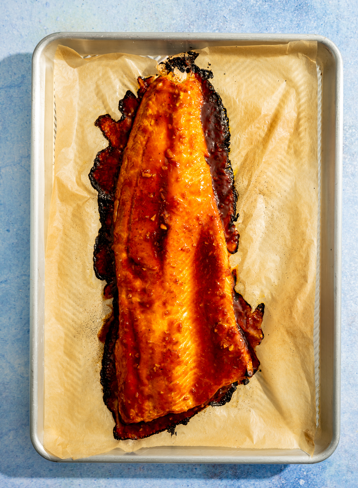 broiled salmon fillet with hot honey glaze on a parchment paper lined baking sheet