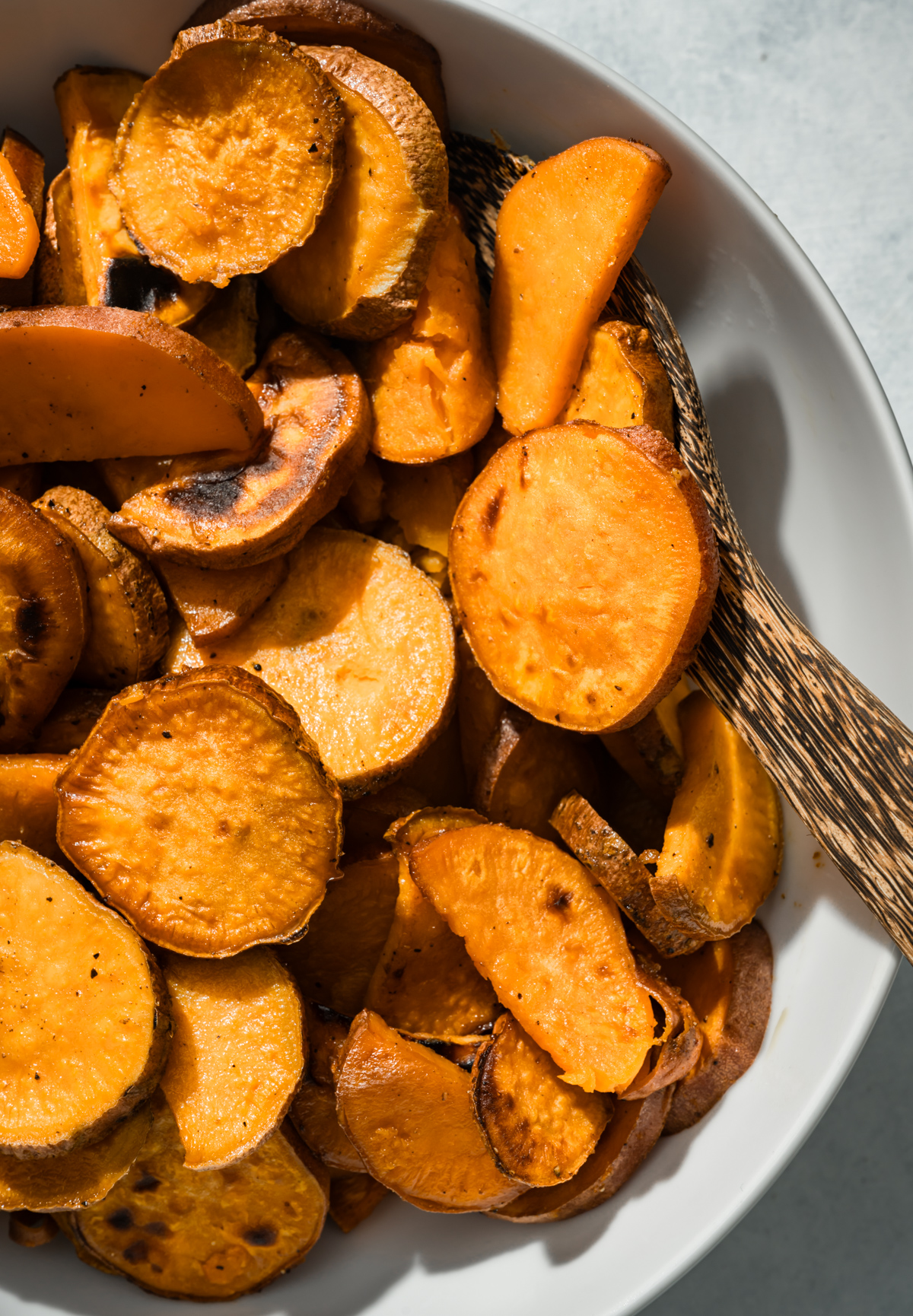 roasted sweet potatoes sliced in a bowl with a wooden spoon