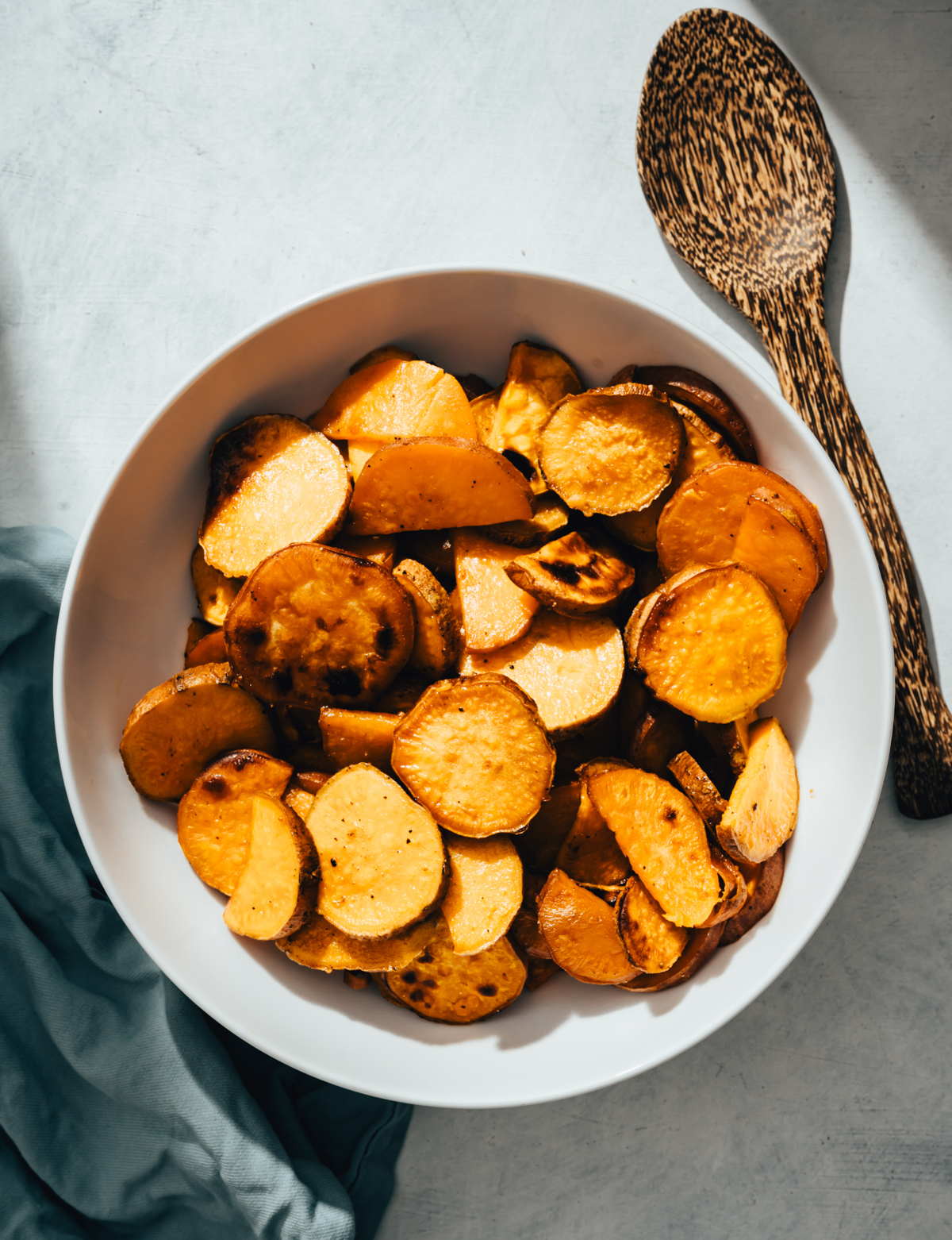 roasted sweet potatoes in a white bowl wooden spoon