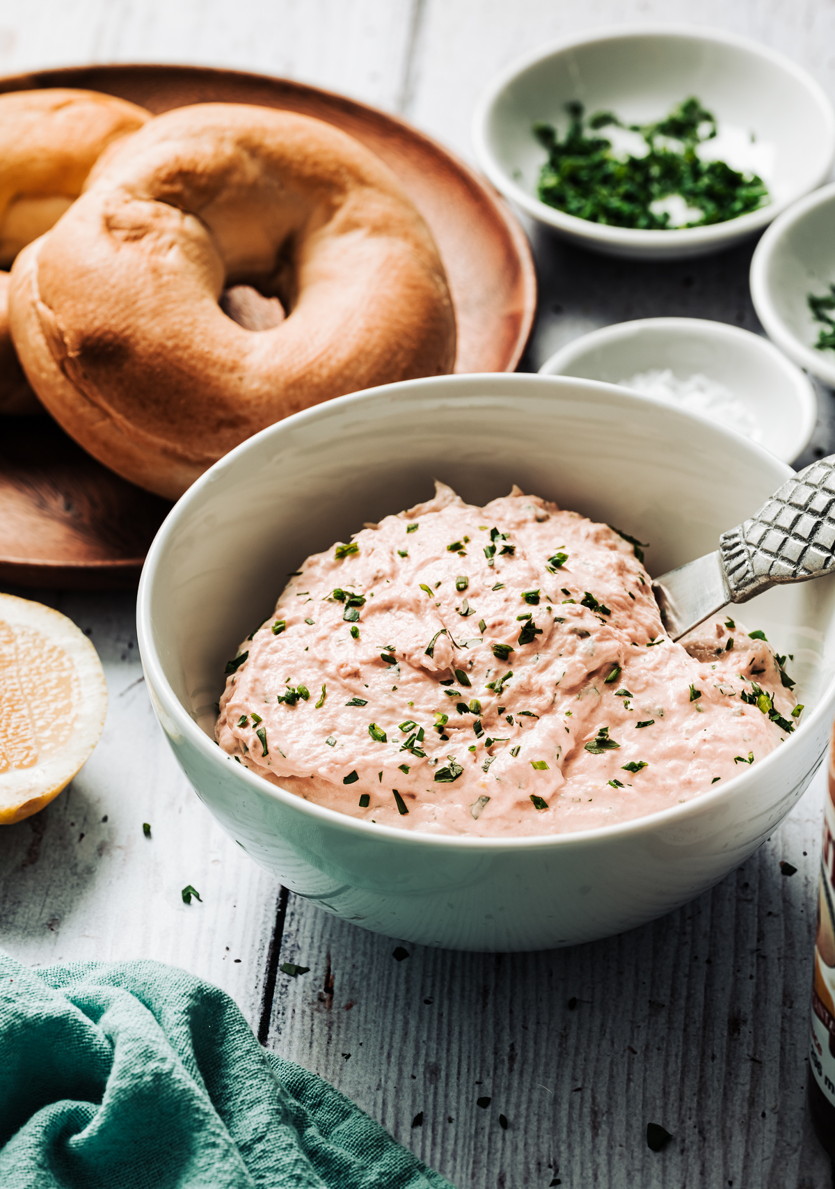 bowl of alsakan smoked salmon spread in bowl plate with bagels dish with minced chives lemon half
