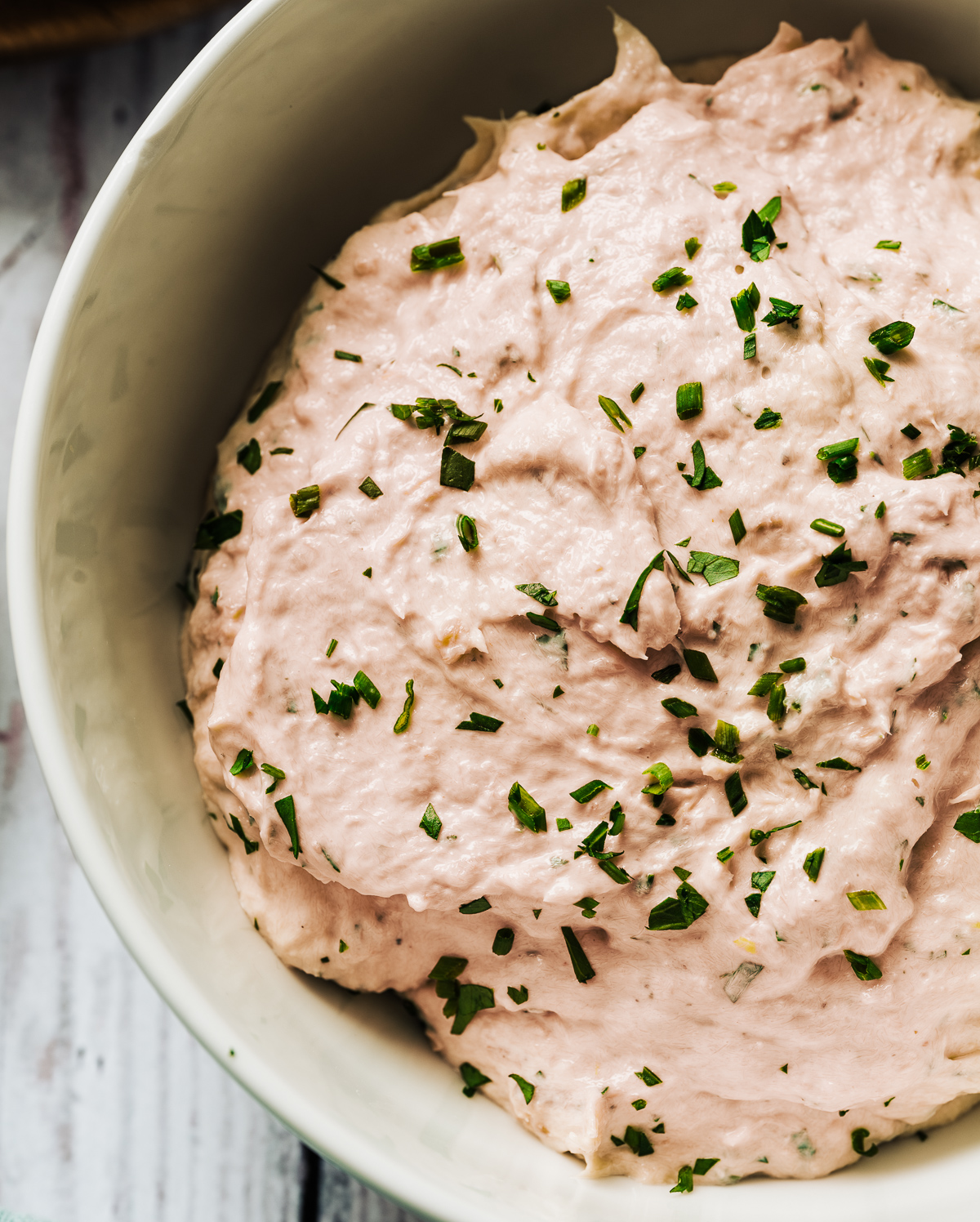bowl of pink smoked salmon spread with green chives and parsley